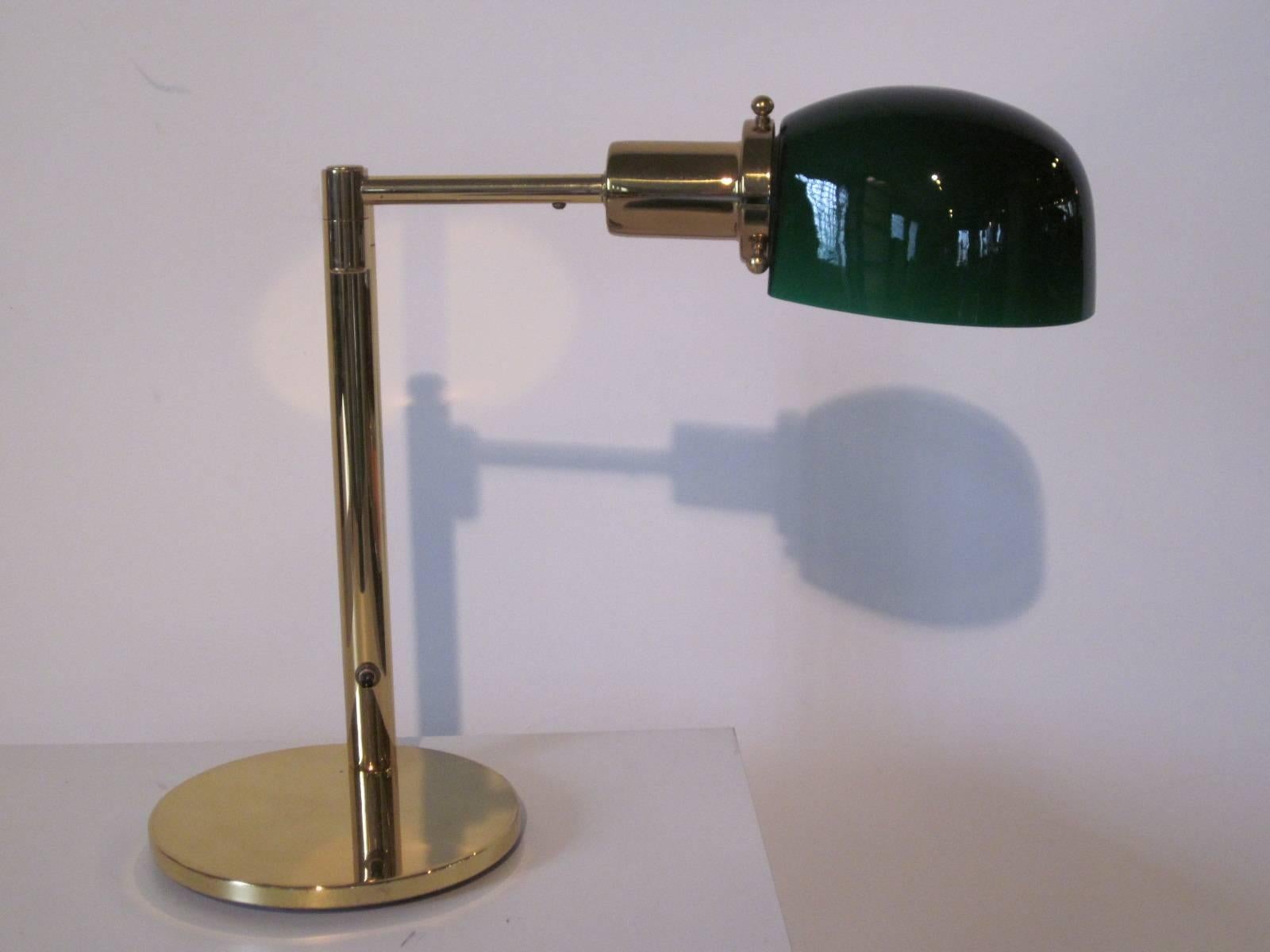 A Nessen brass and green glass shaded swivel arm desk lamp with push button pole switch , the arm swings out to 14.5