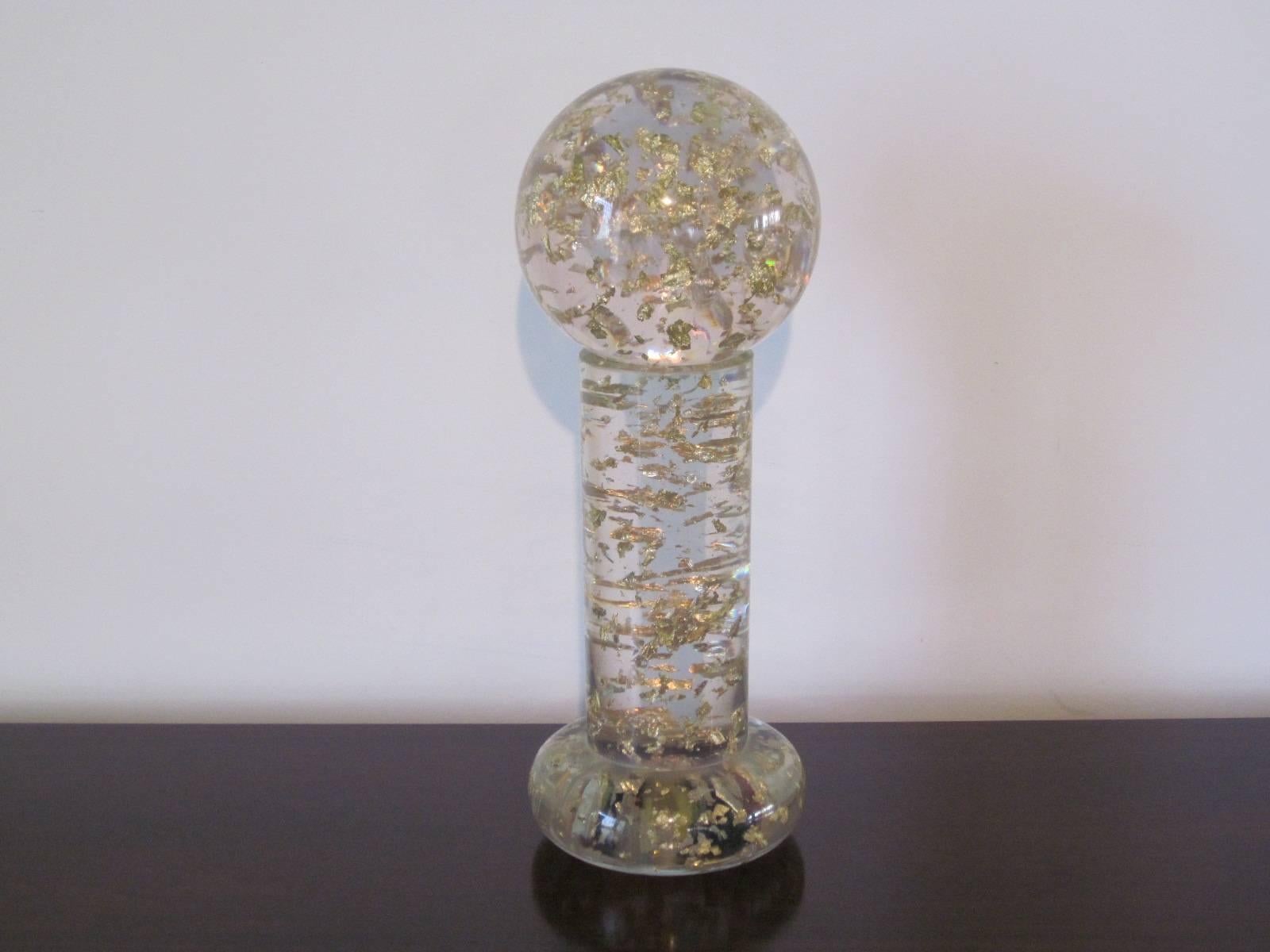 A two-piece Jaru cast Lucite sculpture with embedded 24-karat gold leaf flakes this ball placed on a pedestal sparkles and shimmers playing off any light source giving it a element of added texture. Retains the manufactures label under the removable