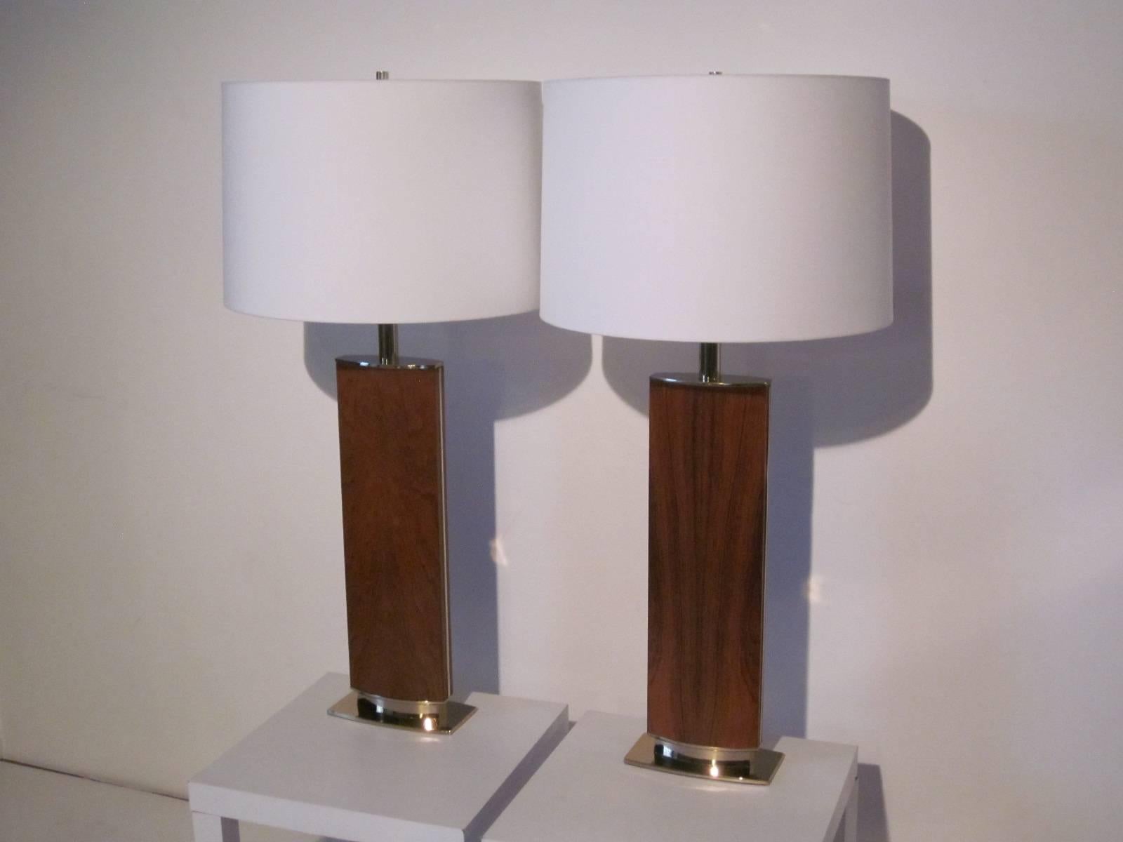 A pair of rosewood bodied table lamps with brass bases, shafts and brass inlaid detail side trim topped with linen shades, well made and heavy manufactured by the Stiffel lamp company. The shade dia. is 19