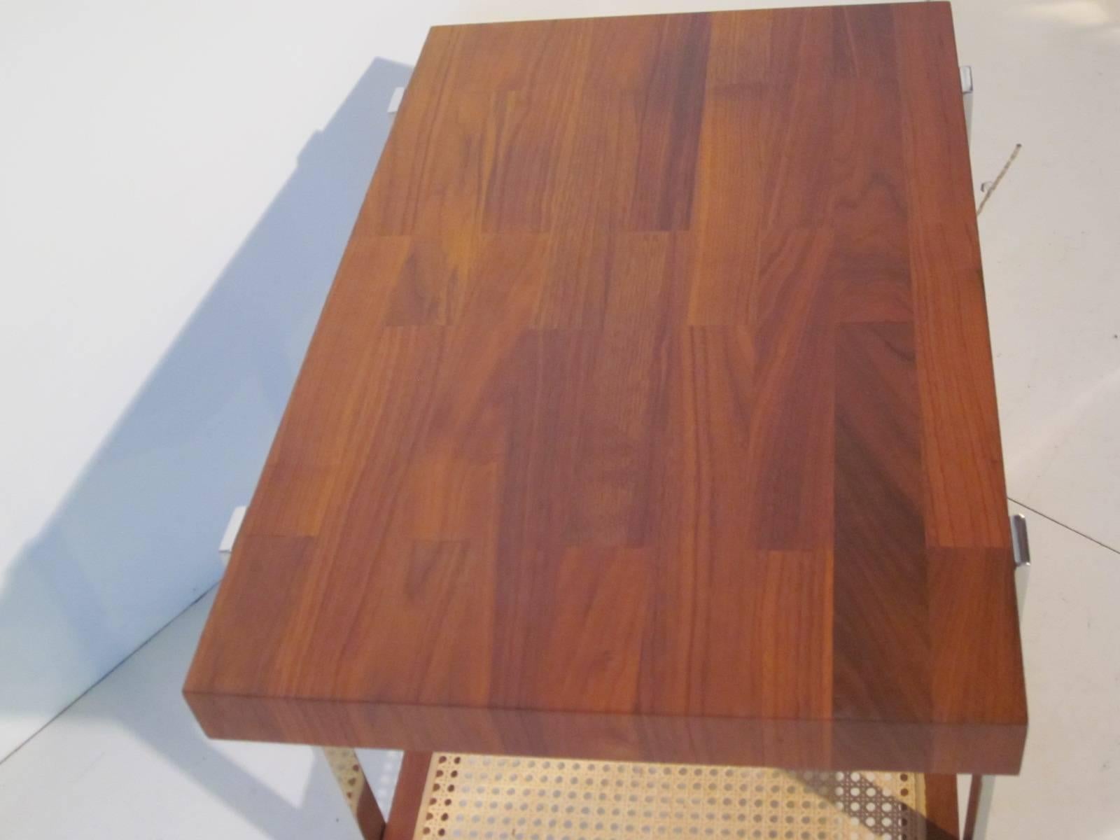 A walnut topped side / End table with chromed legs and lower storage shelve with cane insert in the style of Milo Baughman.