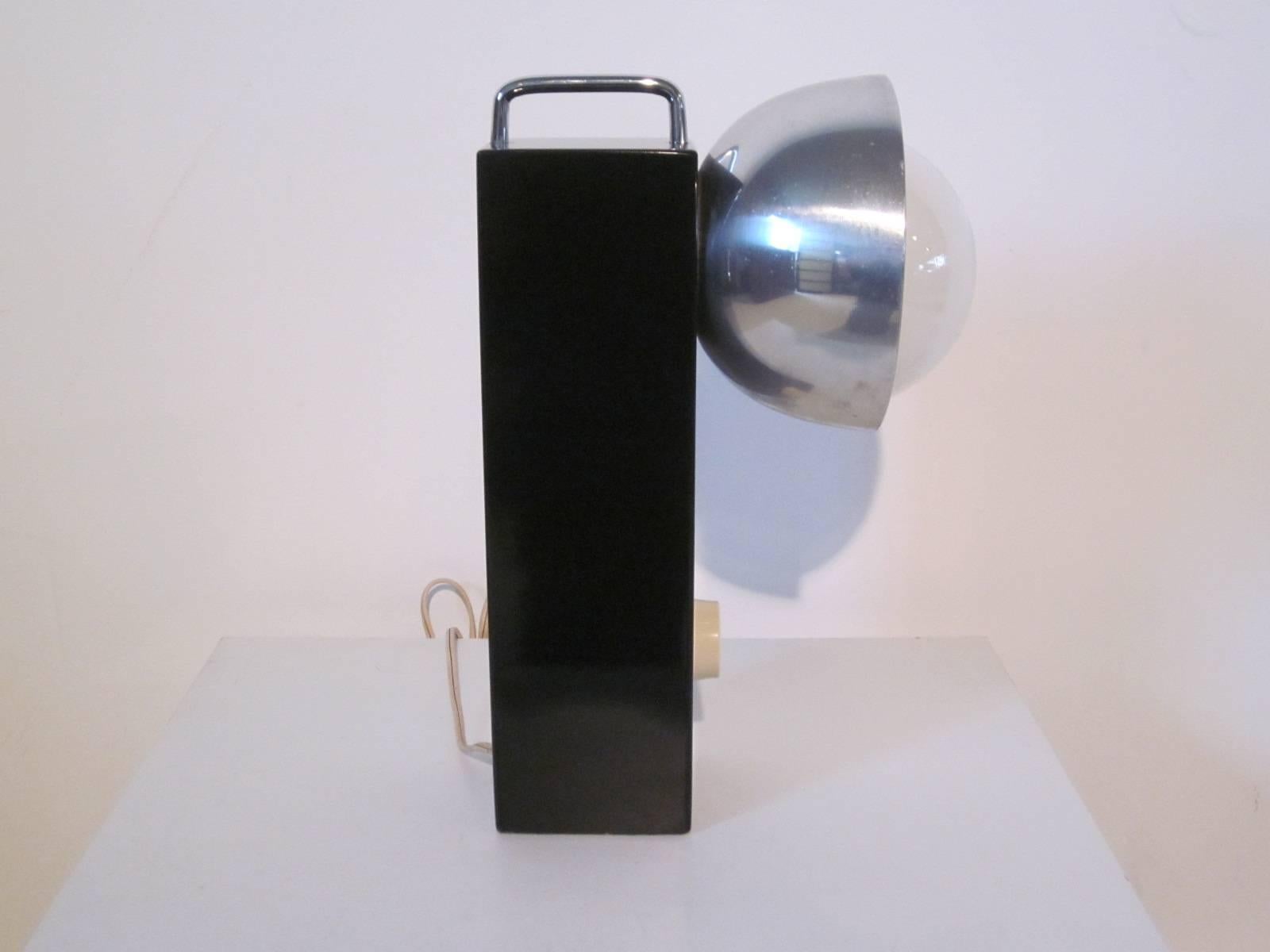 A Mod styled table lamp with black lacquered solid wood base, chrome handle to the top, large aluminum shade to the side with bulb and dimmer switch. Can use a large white ball bulb or a smaller chrome dipped bulb as pictured.