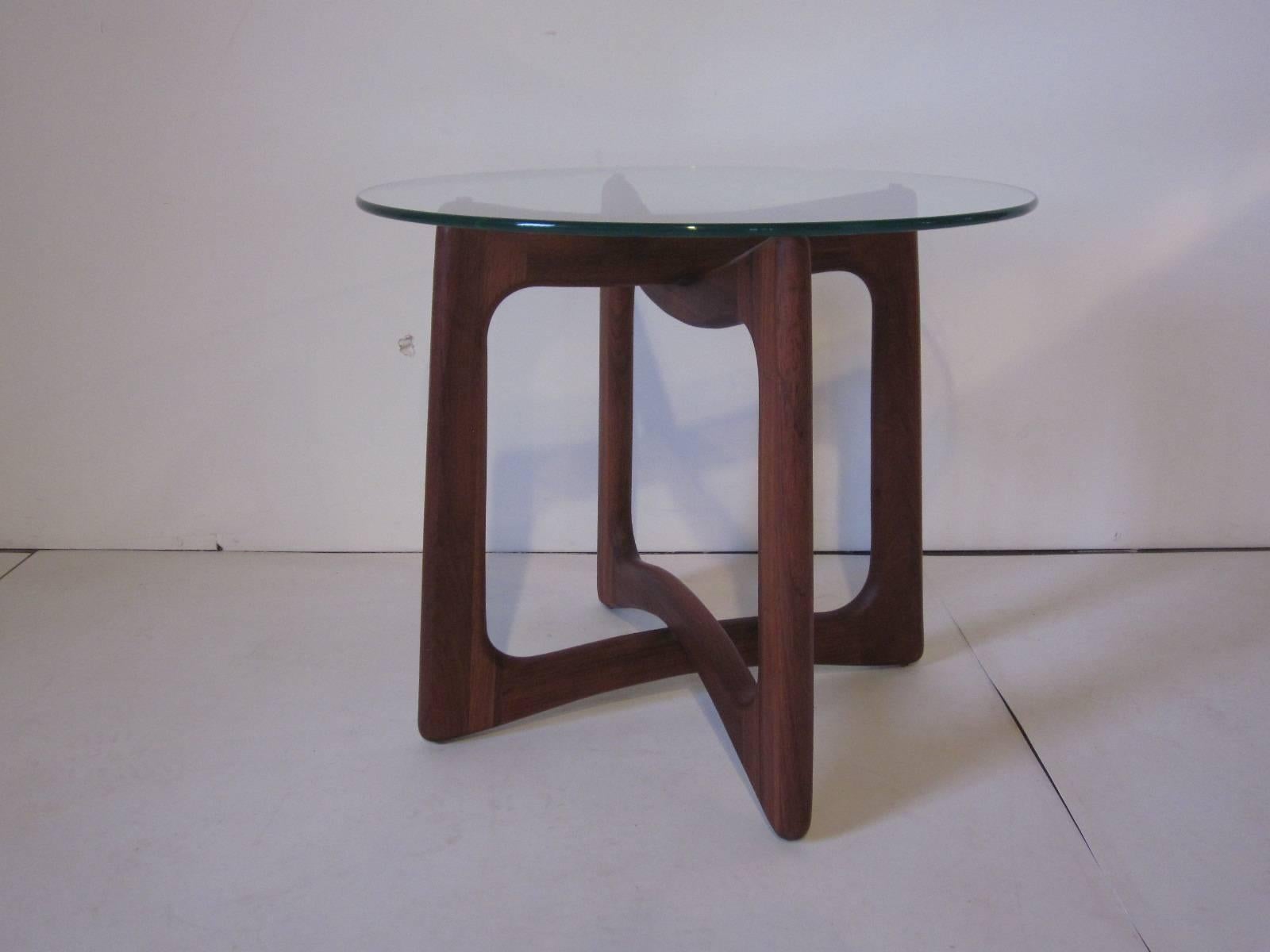 A sculptural solid walnut based side table with glass top manufactured by Craft Associates . 