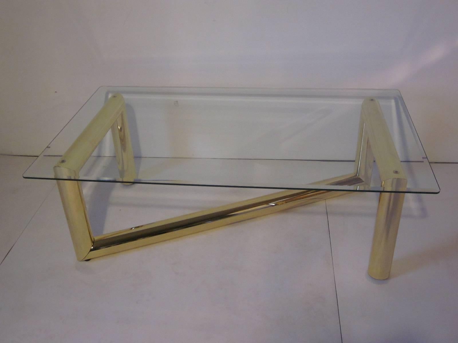 A bold brass tubed coffee table with beveled glass top and Z designed base with adjustable feet and in excellent original vintage condition.