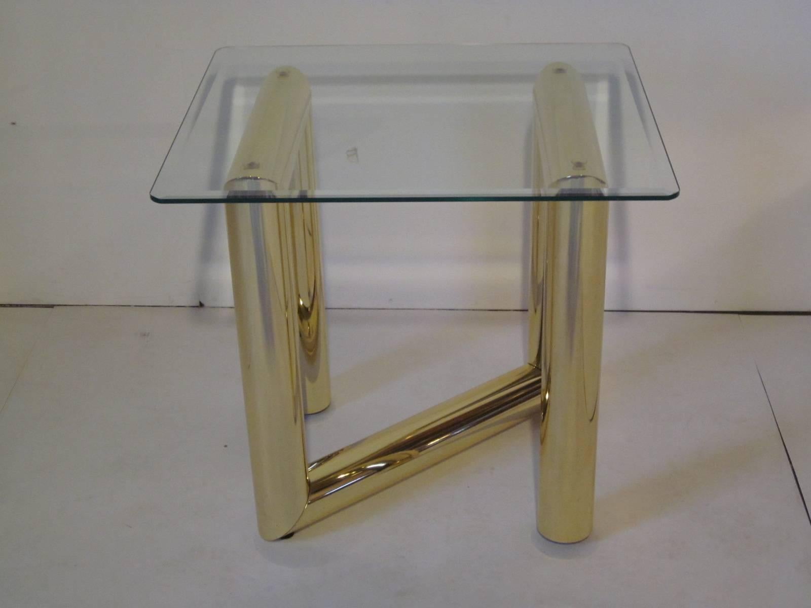 A welded brass tube formed end table with beveled glass top and adjustable feet in the manner of Karl Springer.