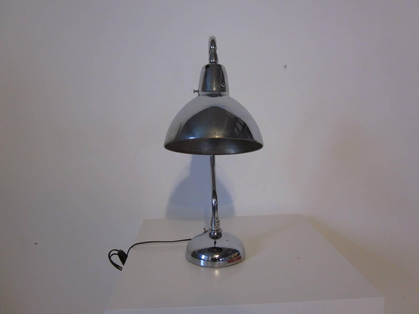 An Industrial styled chromed desk lamp with adjustable bell shade, on and off toggle switch to the base which is weighted and the overall lamp is very well constructed. Manufactured by the Apollo Electric Company, Chicago, IL.