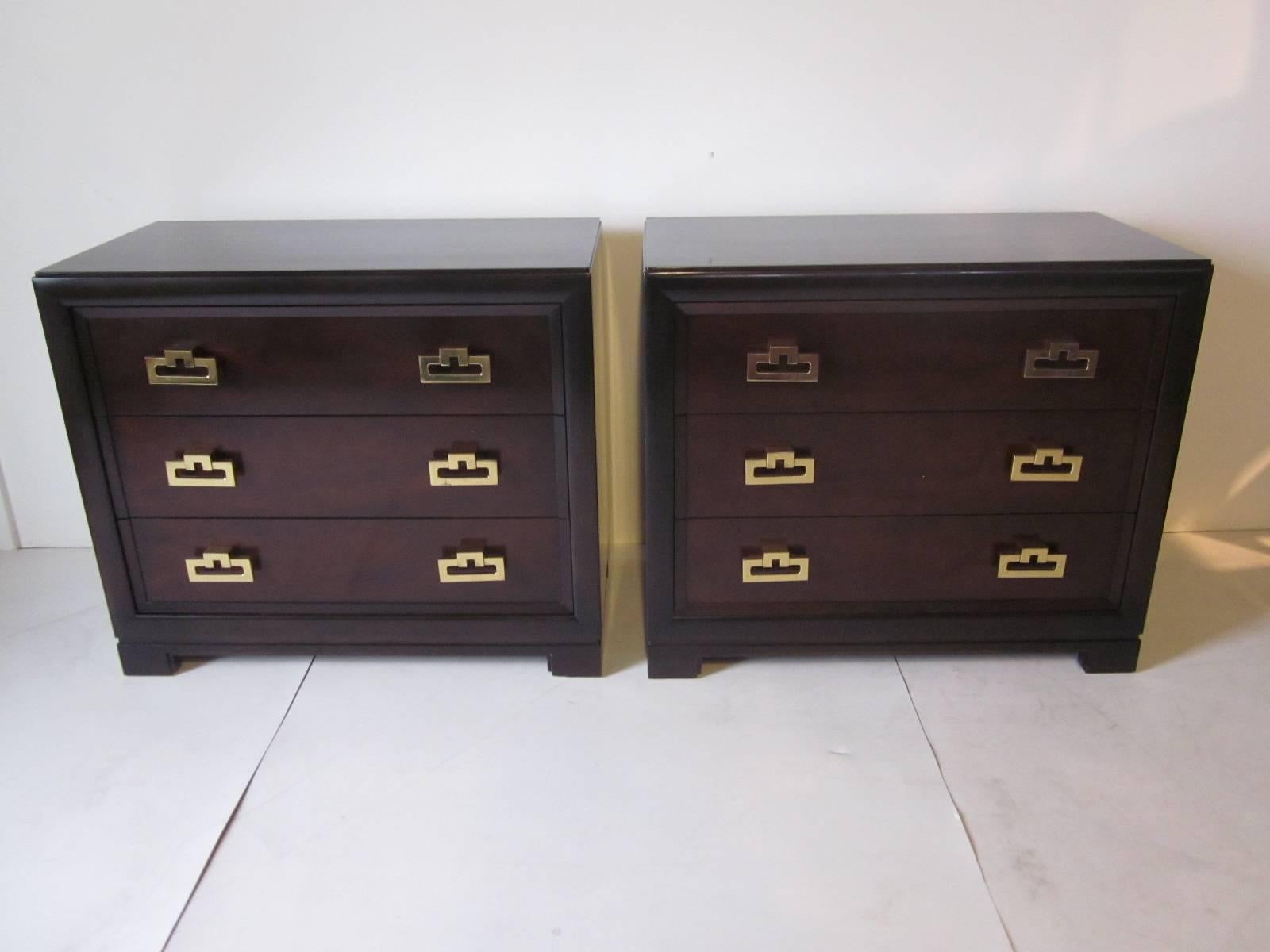 A pair of well crafted wooden chests in an ebony finish to the body and dark mahogany finish to the drawer fronts accented by heavy brass pulls in the style of Dunbar. The upper drawers have dividers and each has a accessory tray which slides from