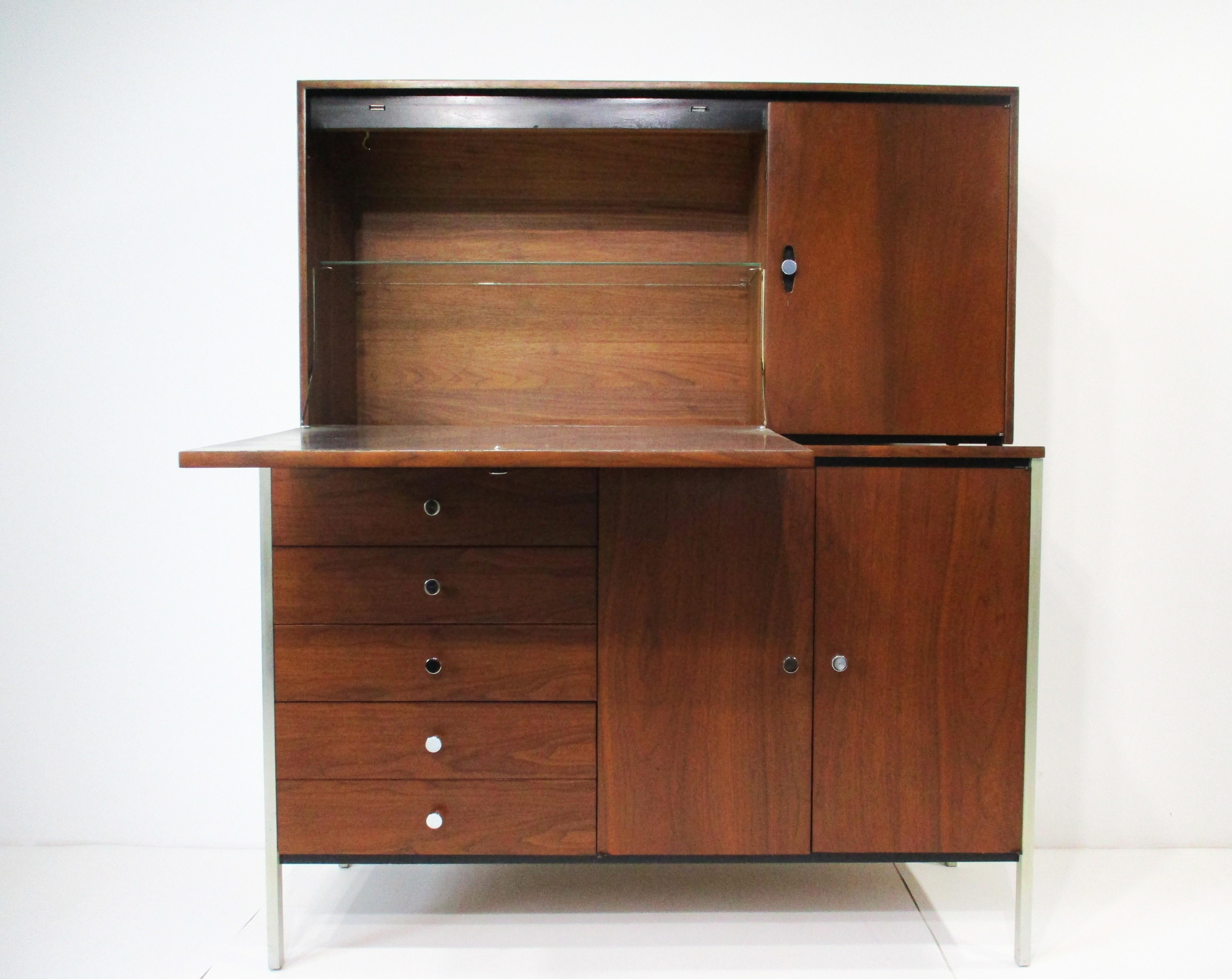 A unique and stunning walnut 2 piece bar cabinet with the top having a pull down door that is also a drink mixing and serving area with an aluminum surface and a upper built in light  . With one adjustable glass shelve and to the right a small