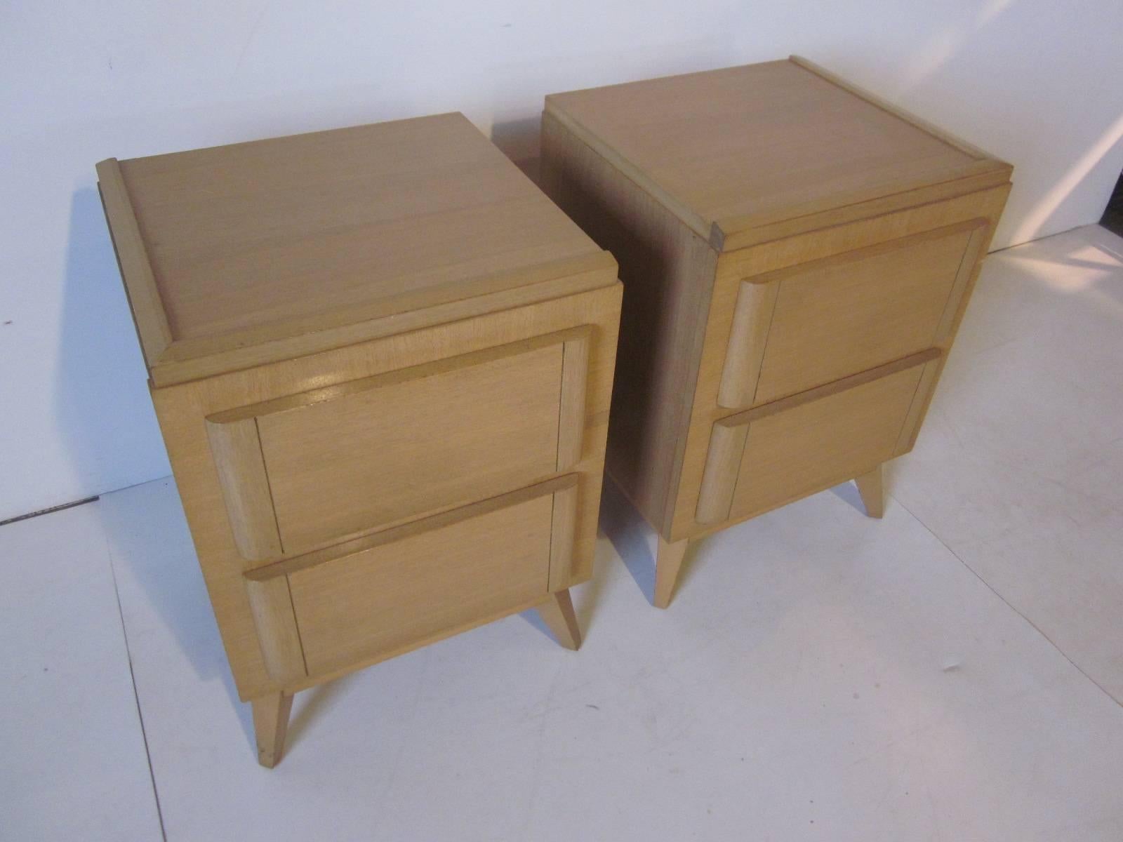 A pair of a honey toned mahogany nightstands in the style of Eliel Saarinen with two drawers and splayed legs, retains the manufactures branded mark to the drawer R Way Furniture company.
