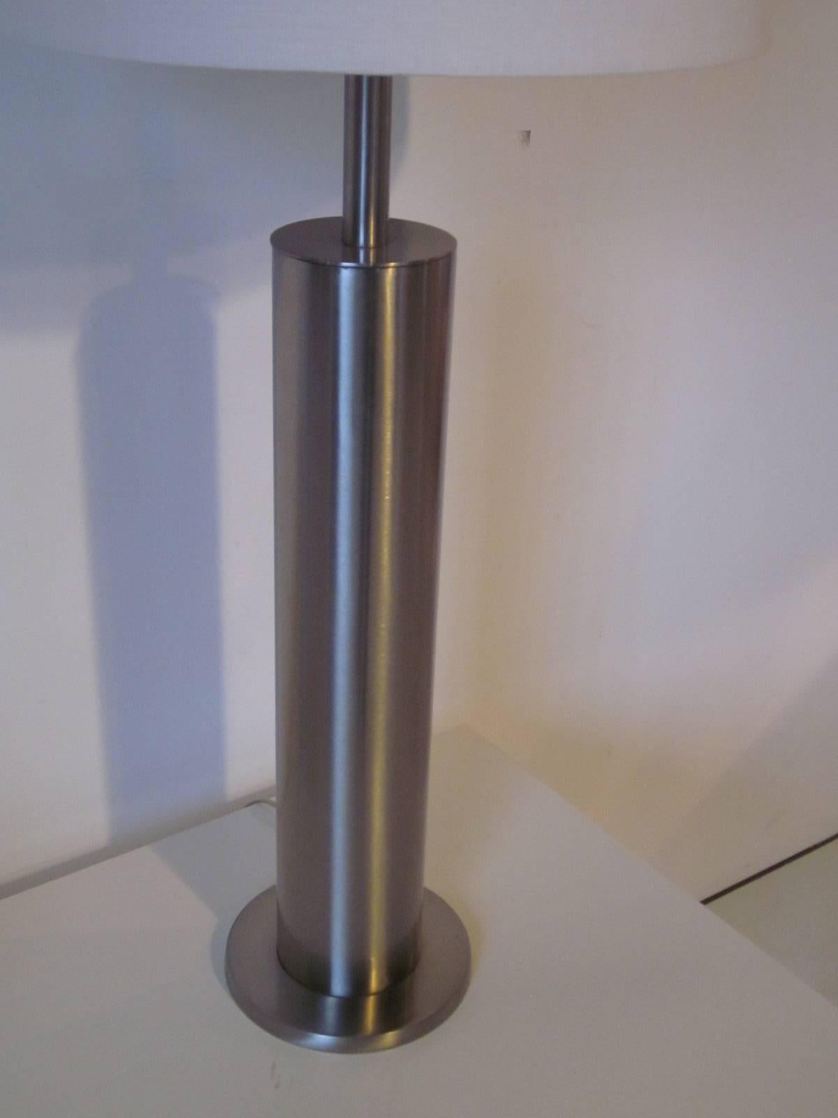 A brushed stainless table lamp with bone white linen shade manufactured by the Laurel Lamp Company.