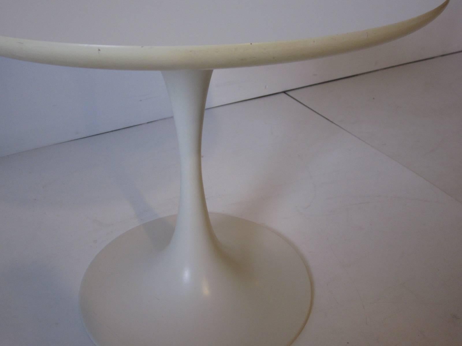 A Knoll styled white tulip side table with laminate top and sculptural steel base in a satin finish. Designed in the manner of Eero Saarinen and manufactured by the Burke Furniture Company.