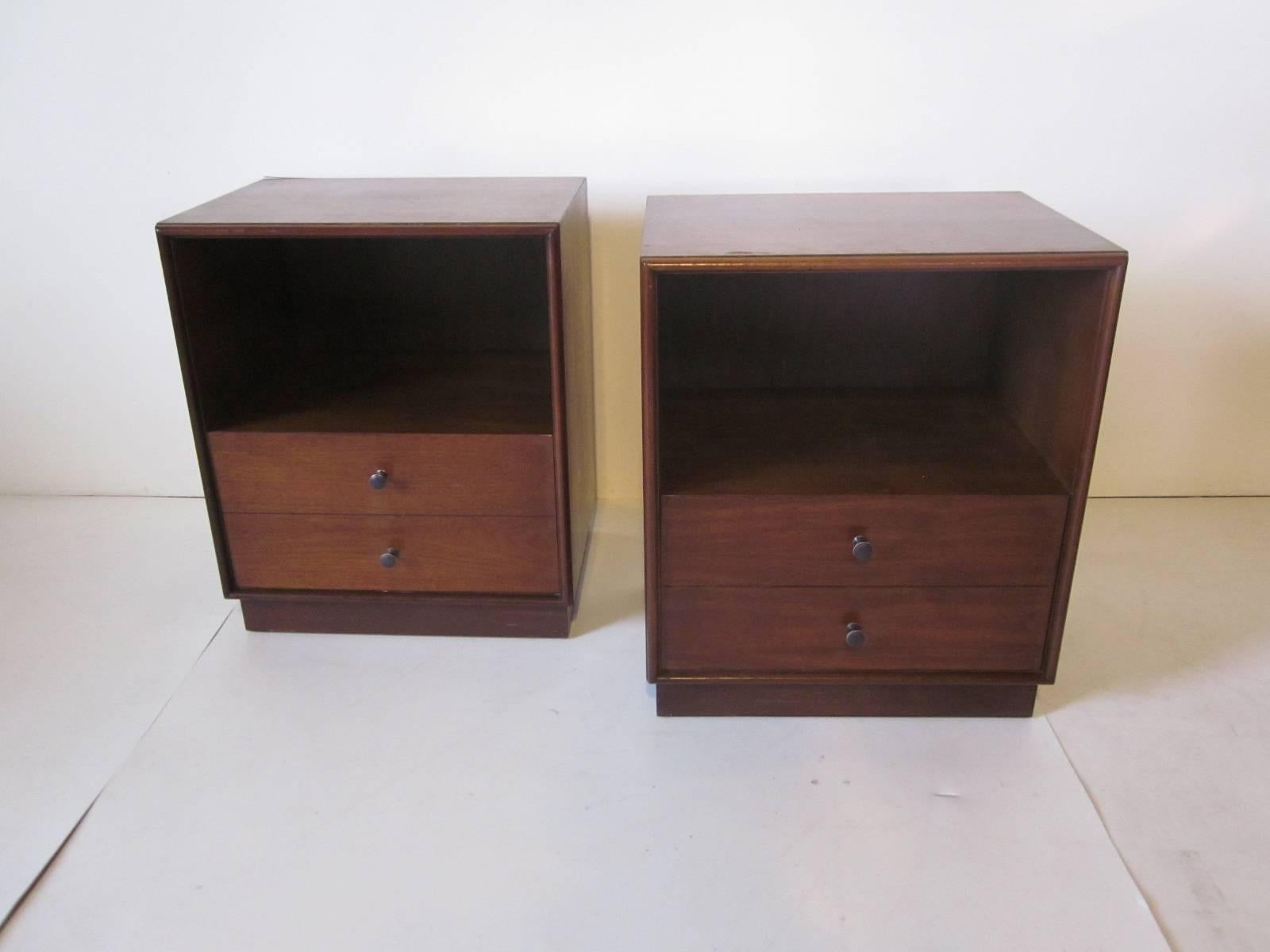 A pair of Mid-Century nightstands in dark walnut with lower single drawer and bronze styled pulls with upper storage area in the style of Harvey Probber.