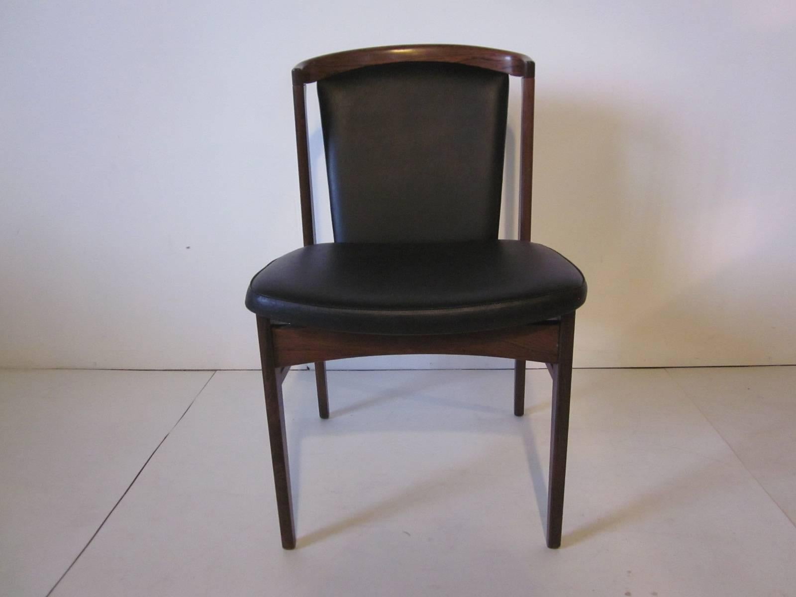 A pair of dark rosewood framed chairs with rich black vinyl upholstery retaining the manufactures ink stamp to the seat bottoms “Erik Christensen, made in Denmark designed by Eric Buck.