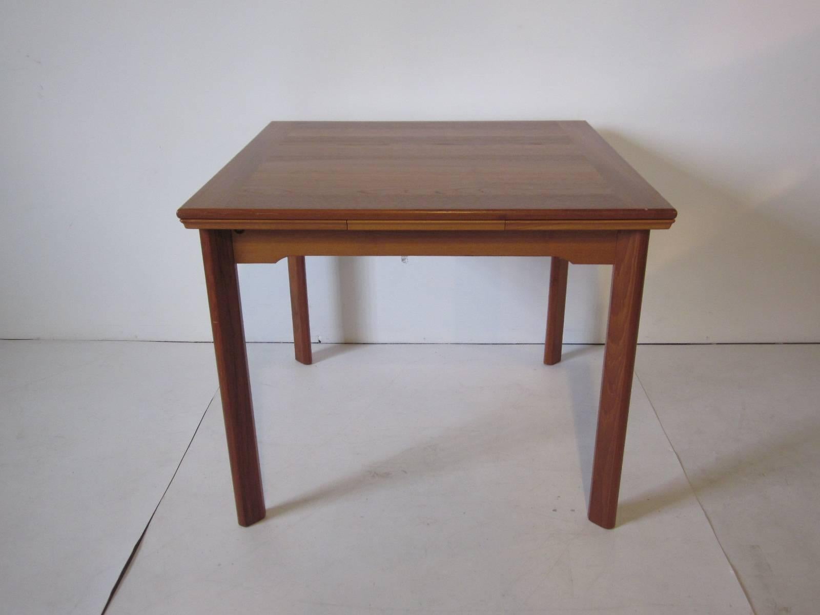 A petite sized teakwood dining table with pull-out leaves to each end, Retains the manufactures tag Made in Demark by Uldum Mobelfabrik . Measurement closed is 34.50