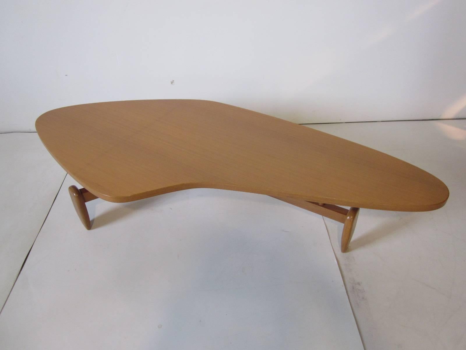 A mahogany coffee table with biomorphic floating top and solid mahogany architectural stretcher base and feet. Marking to the bottom from the manufacture Brown-Saltman.
 