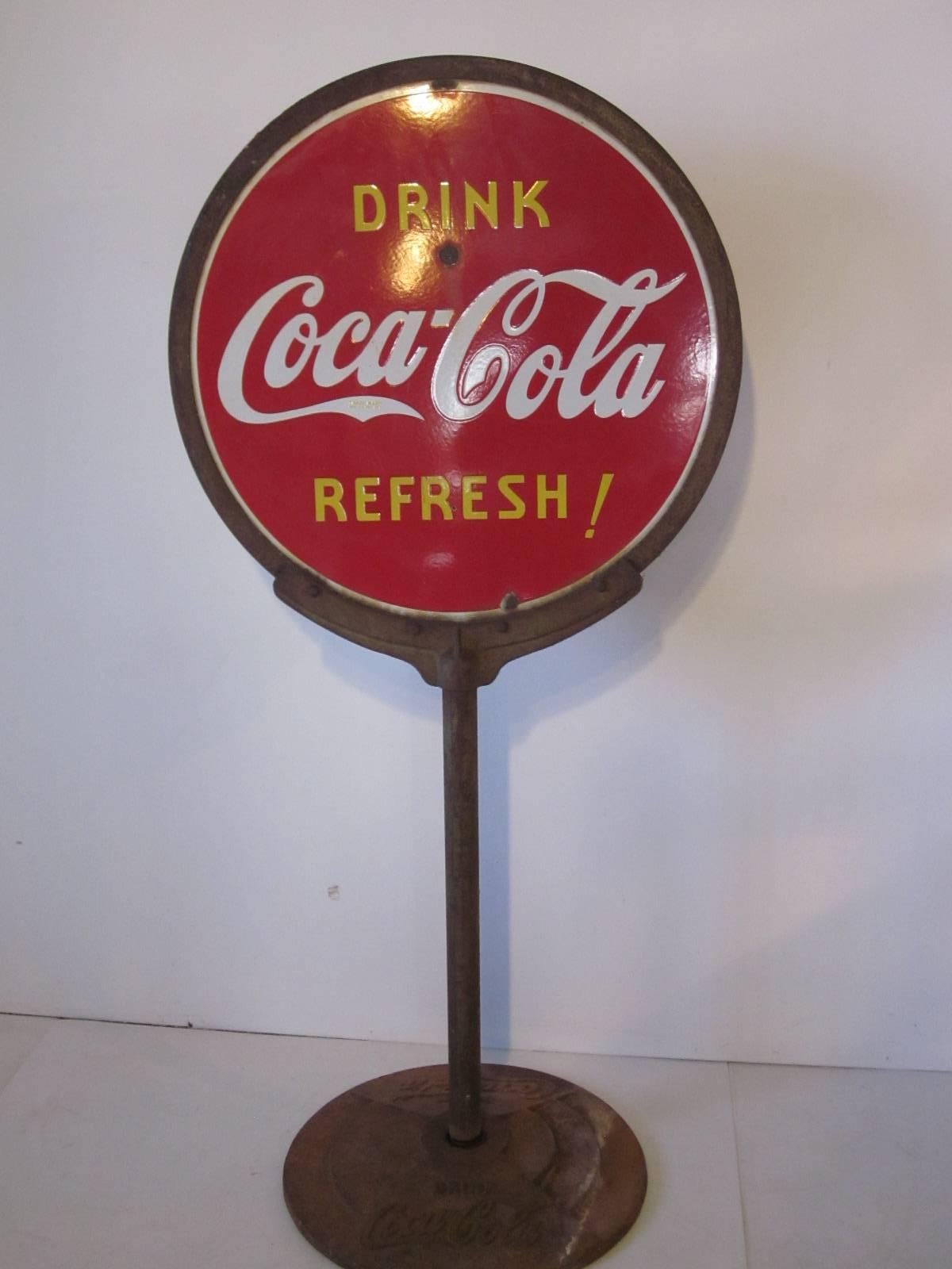 A porcelain enameled Coca Cola Lollipop sidewalk sign with original frame and embossed steel base inscribed with drink Coca Cola. The two-sided sign has the slogan 