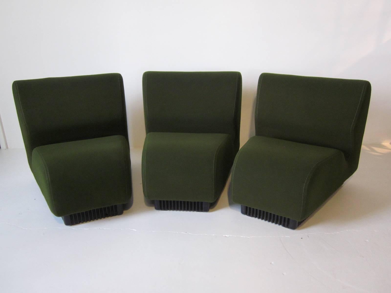 A three-piece pie shaped modular sofa set in olive green using smooth and soft contract fabric sitting on black corrugated ABS plastic bases. They can be used as individual seating or together as a sofa, manufactured by the Herman Miller furniture