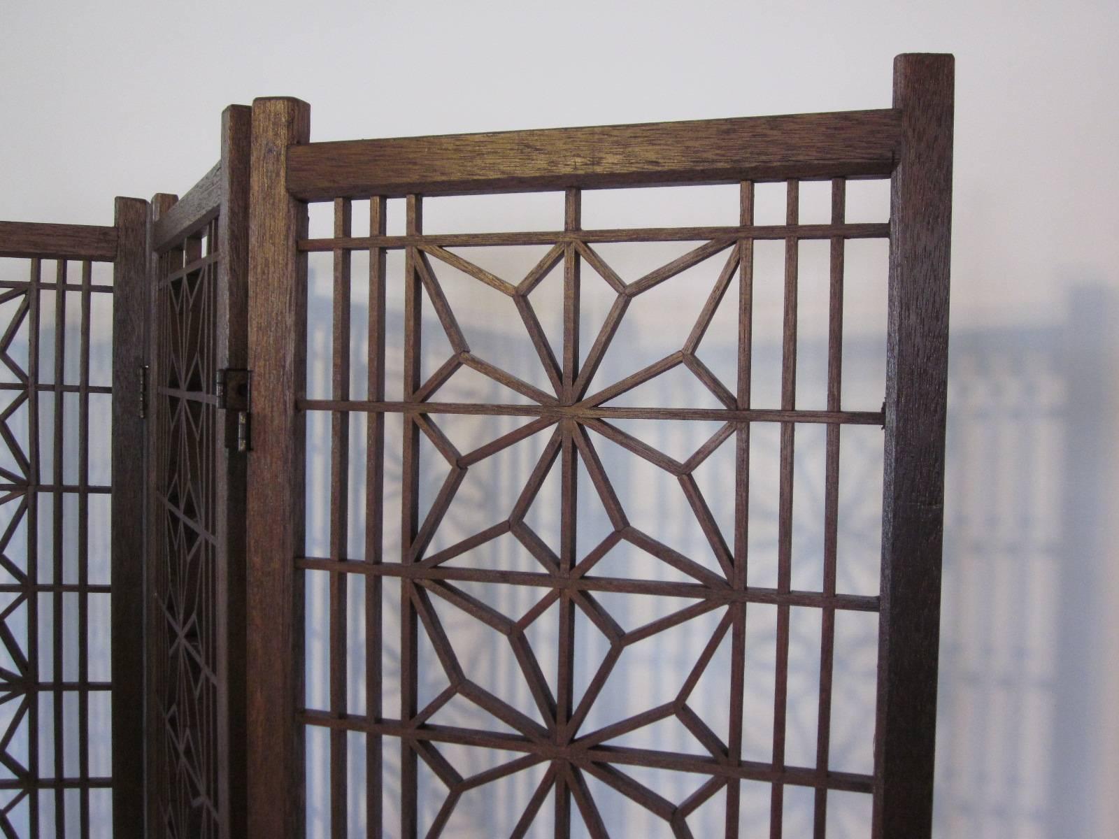 A four-panel room divider with a single piece geometric constructed wood design and lower woven wood bottom section.