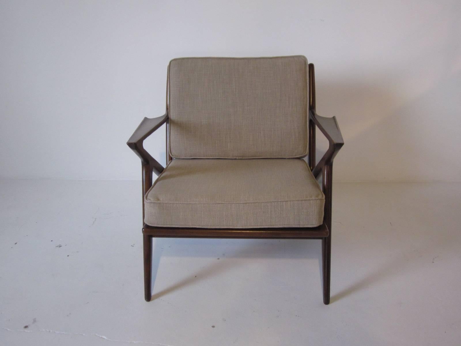A sculptural wood-framed armchair with loose back and bottom cushion in a dark walnut finish, made in Denmark. Two back supports have been replaced.