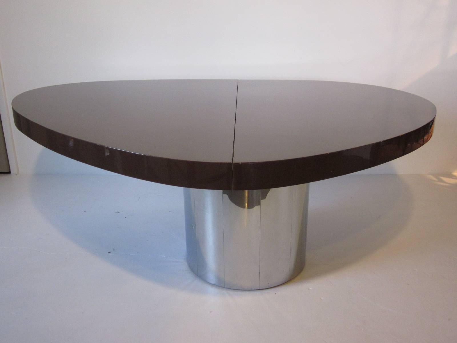 A 1970s dining or conference table designed by Paul Evans with dark chocolate brown heavy lacquered wood top. Two brushed stainless steel laminate leaves at 18.50