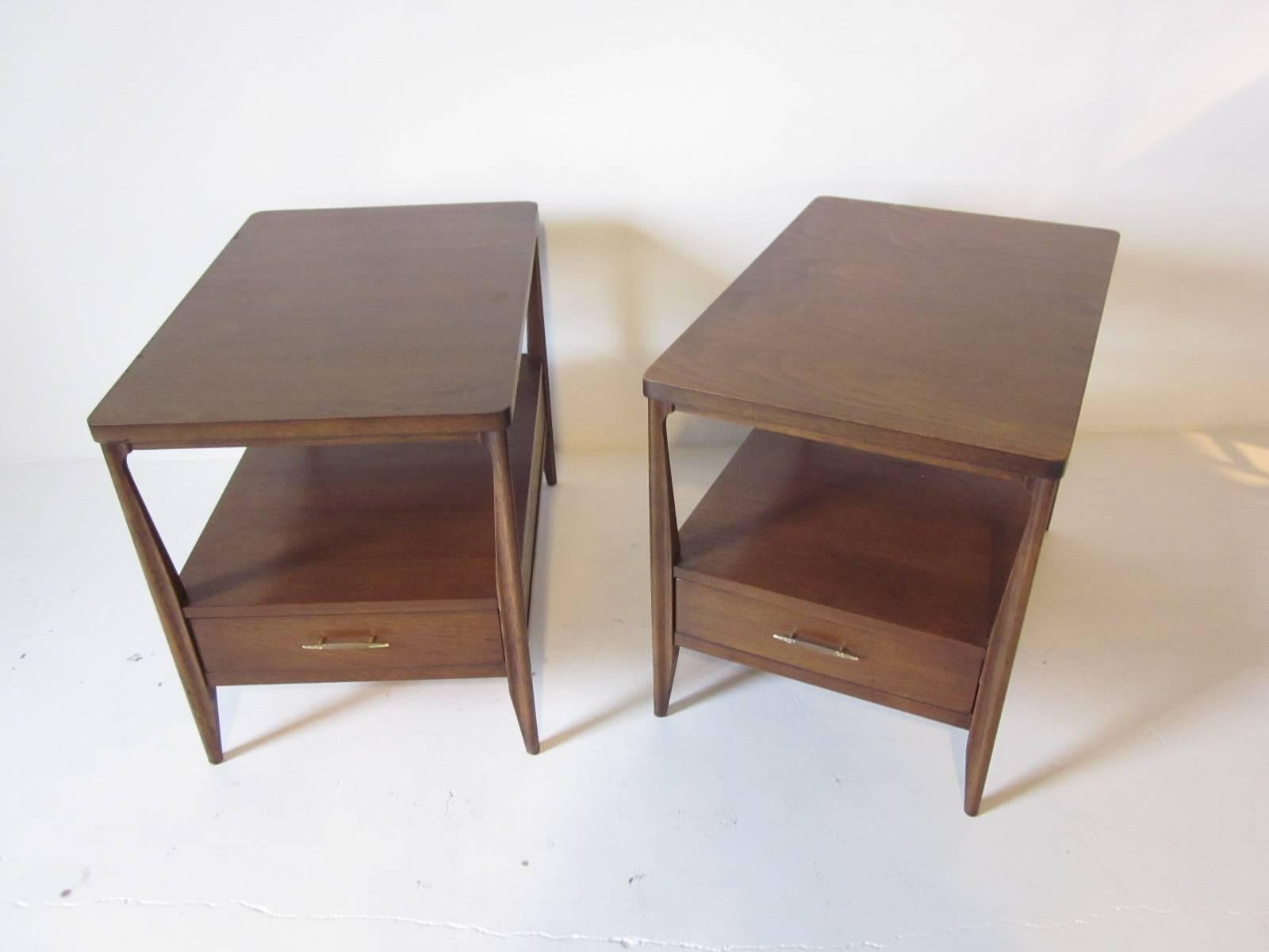 A pair of dark mahogany Mid Century nightstands or end tables with lower single drawer, brass detailed wood pulls and tapered legs.