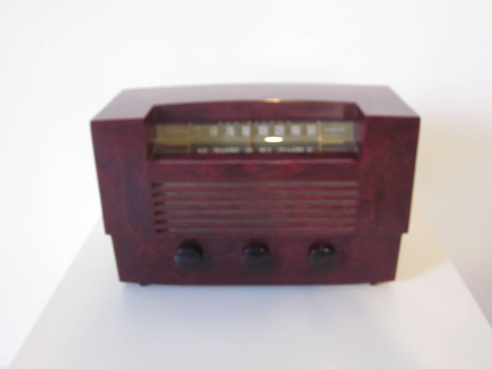 A mahogany red Catalin marbleized RCA radio with standard and short wave stations, three large knobs and glass station cover, model # 66X8, retains the paper label to the bottom manufactured by the RCA Victor company.