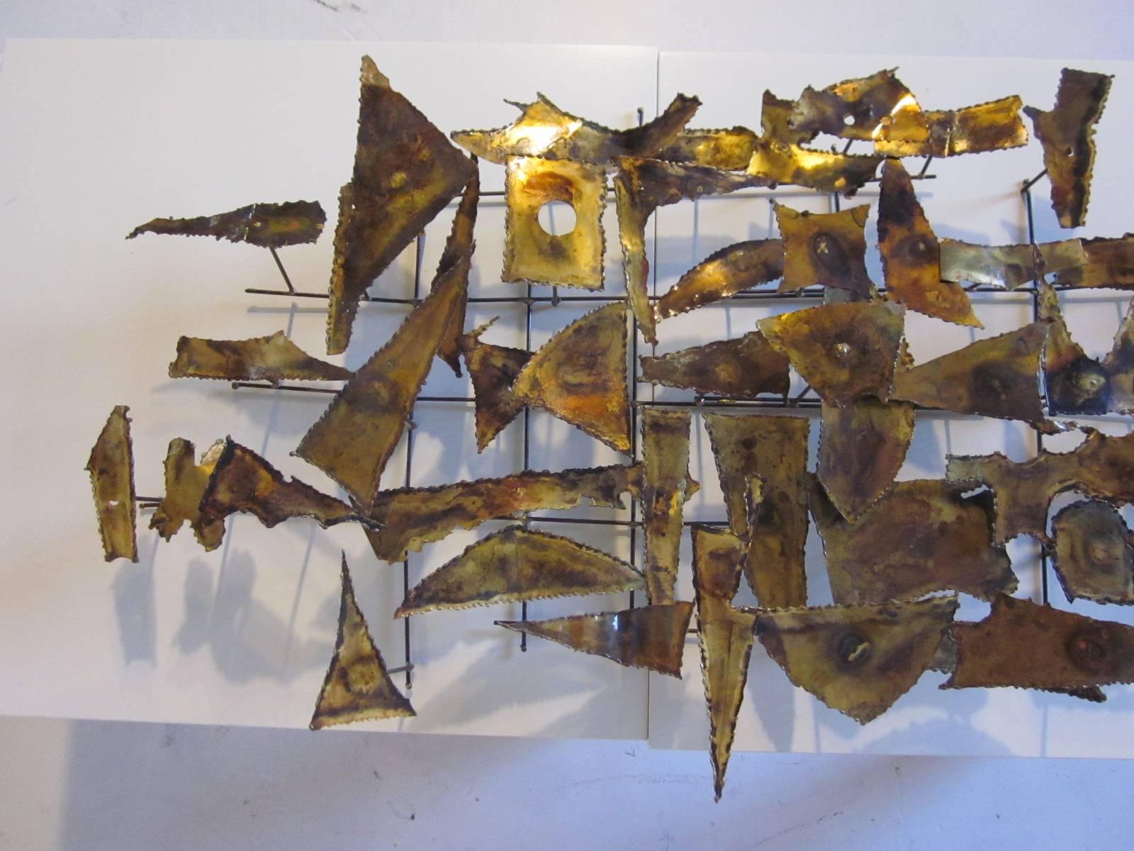A Jere styled Brutalist brass, copper and torch cut wall sculpture with angled metal design.