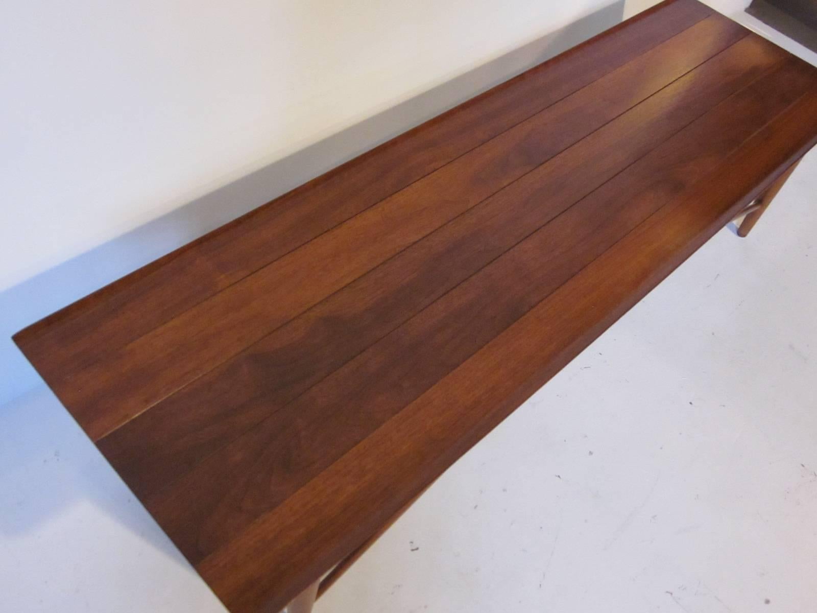 A beautifully grained Henredon coffee table with planked top in the style of Dunbar's Long John Bench table, turned up edges, single middle drawer and leg supports. Featuring a great design and constructed with the highest level of craftsmanship.