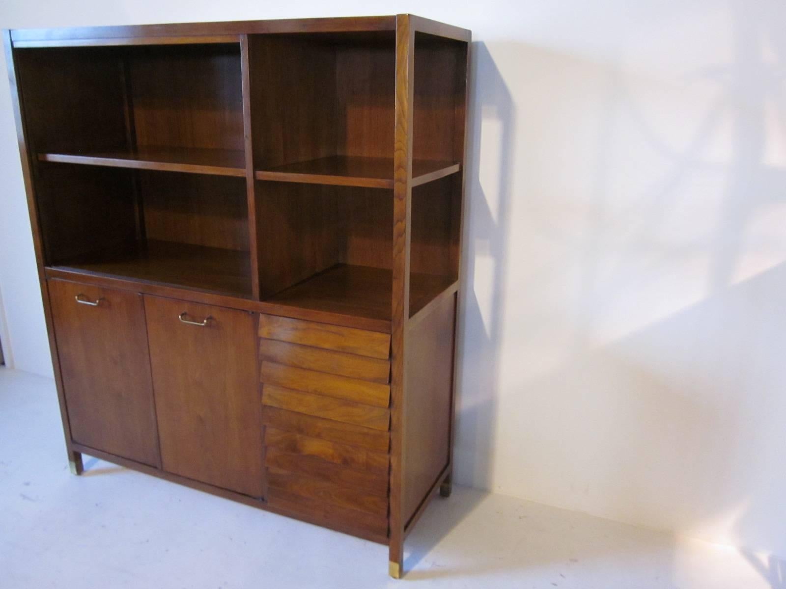 A tall hutch with credenza base, two doors and shelve for storage and four drawers, open top shelves that can be used for a bookcase, china hutch or the entertainment area. Brass pulls and leg caps with angled front drawers complement this one piece