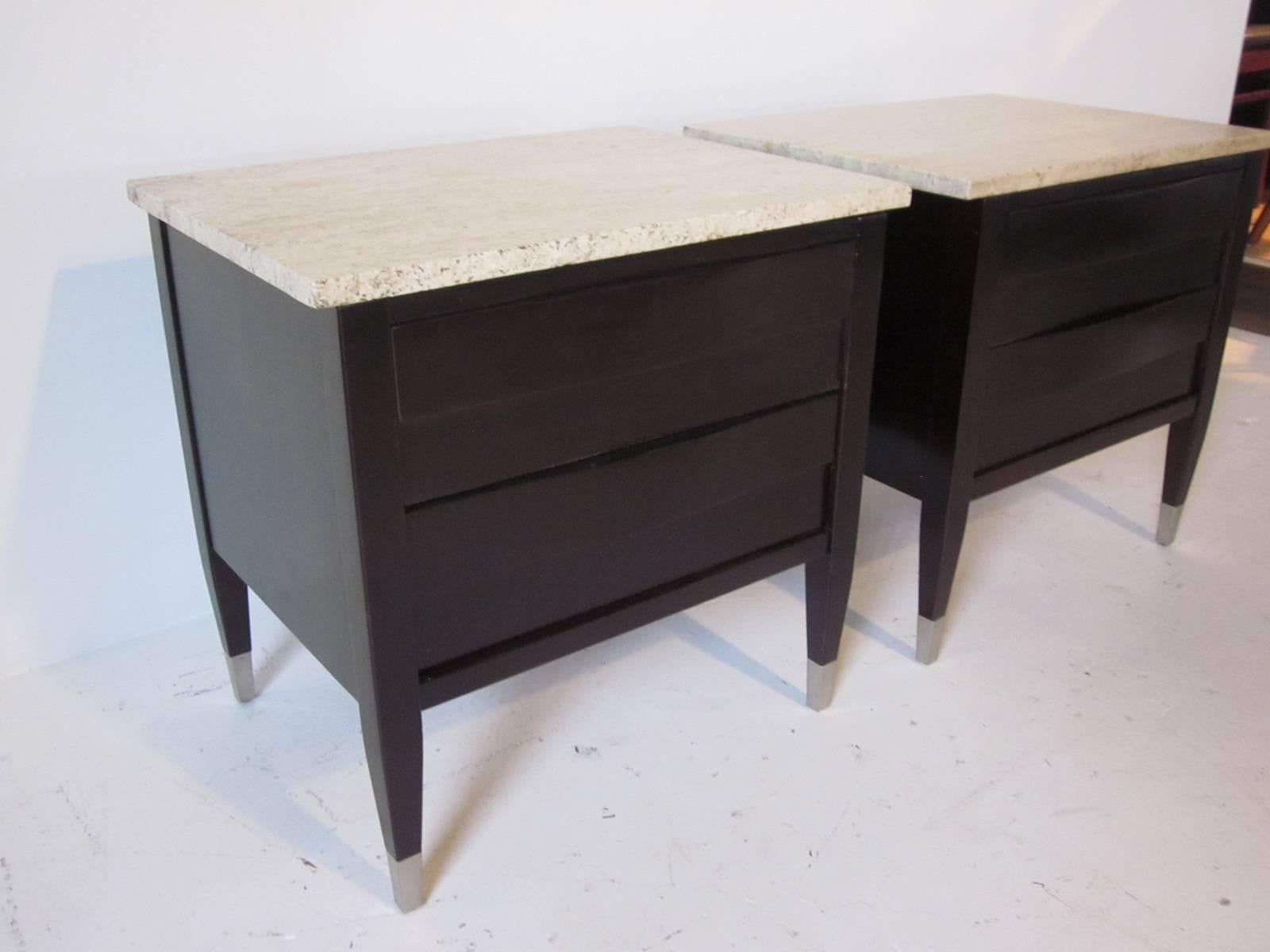 A pair of nightstands in a dark ebony finish with travertine marble tops and two lower drawers, stainless metal foot caps complement the piece manufactured by American of Martinsville.