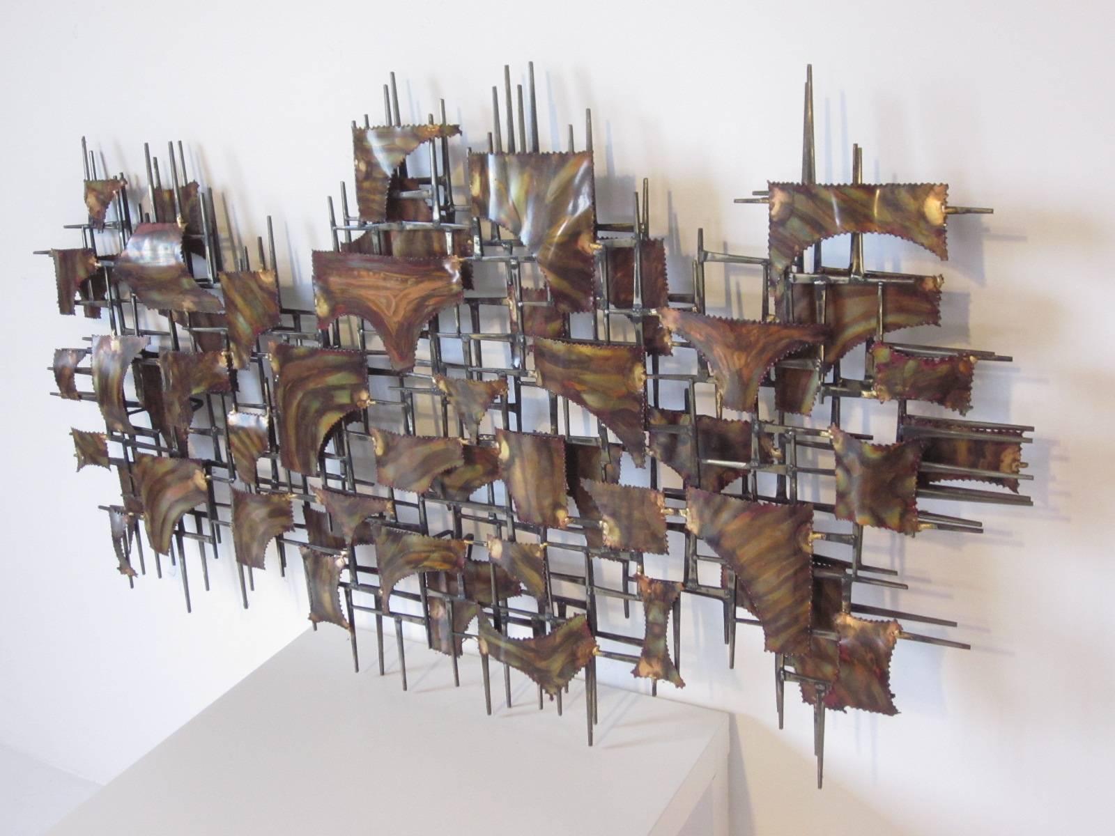 A torch cut, flamed and welded large metal wall sculpture in copper and brass tones contemporary in design with built in rear wall hangers so it can be displayed vertically or horizontally. In the manner of artist Silas Seandel.