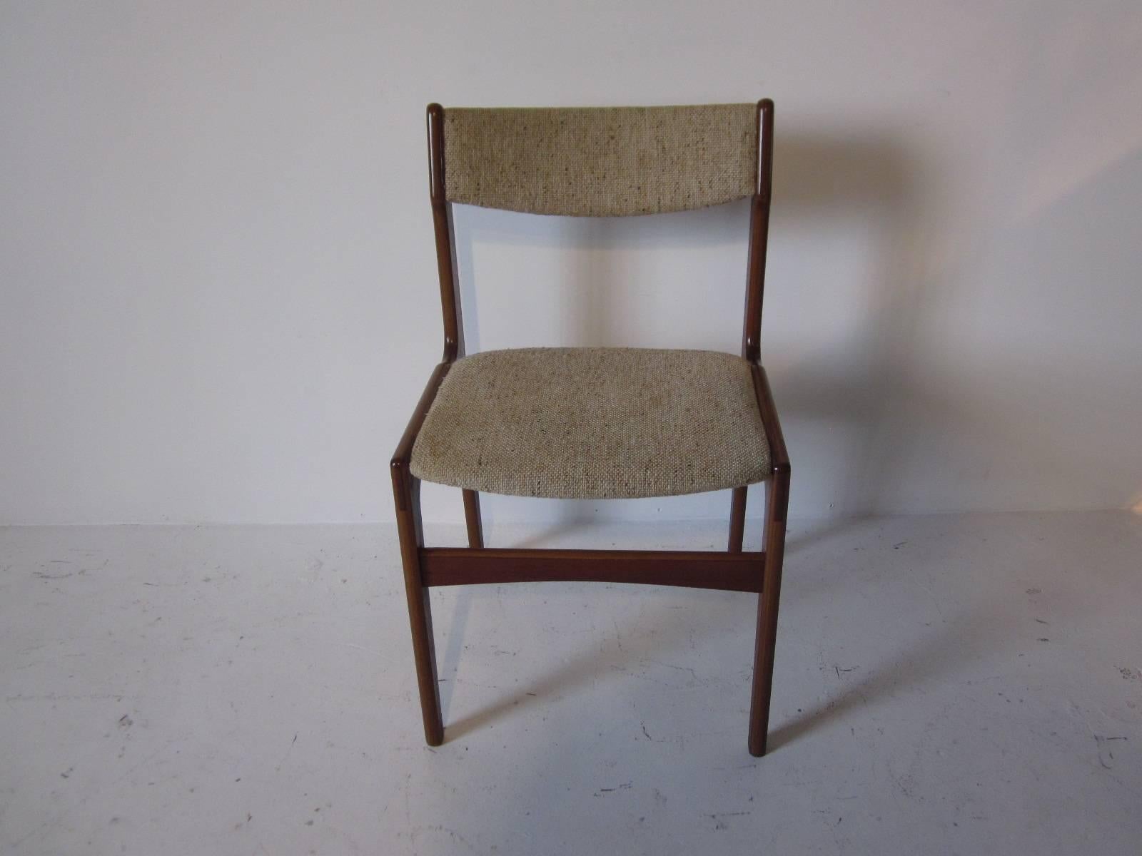 A set of four teak framed dining chairs with wool blend oat meal toned upholstery, made in Denmark.