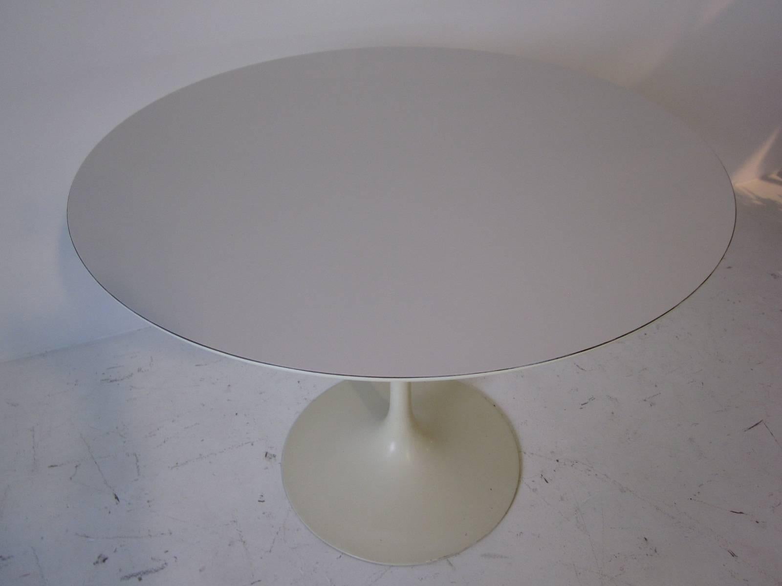A smaller sized dining or cafe tulip table with white laminate top and cast metal leg manufactured by Knoll.