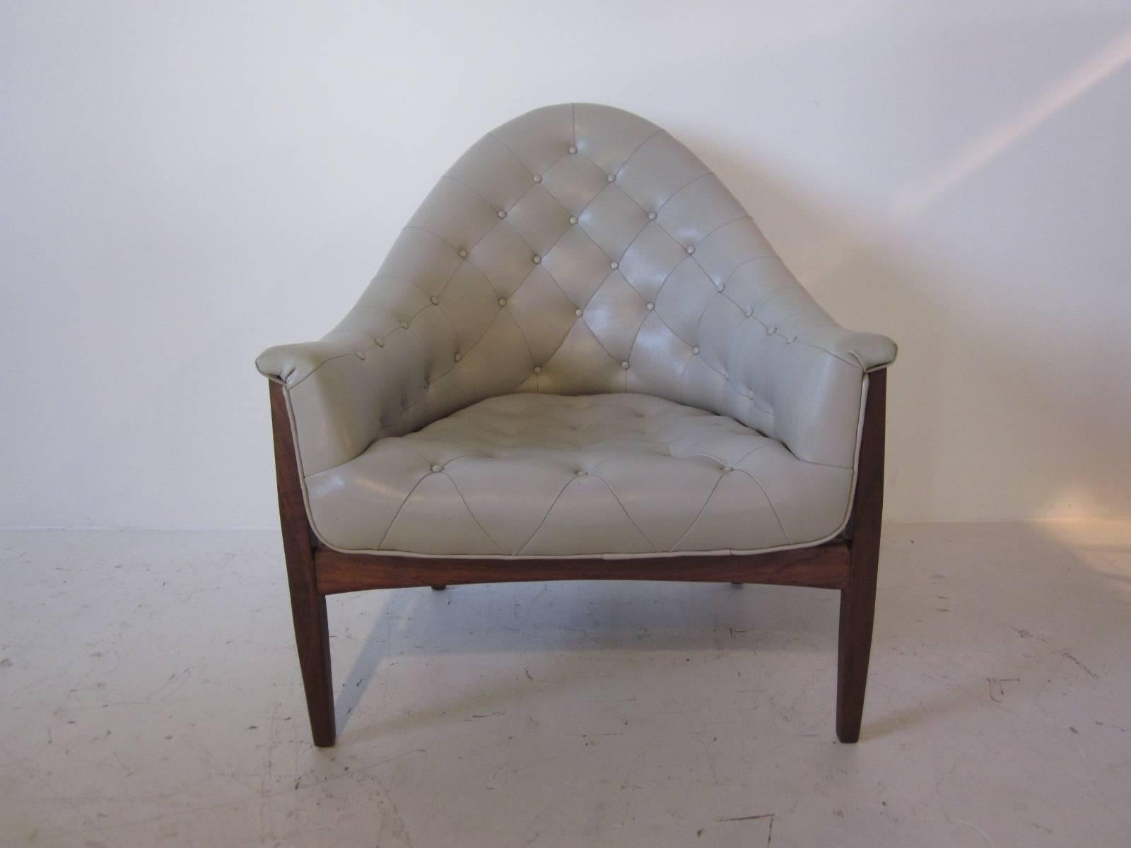 A tufted leatherette upholstered lounge chair sitting on a medium dark walnut frame, retains the manufactures tag Thayer Coggin Furniture company designed by Milo Baughman.