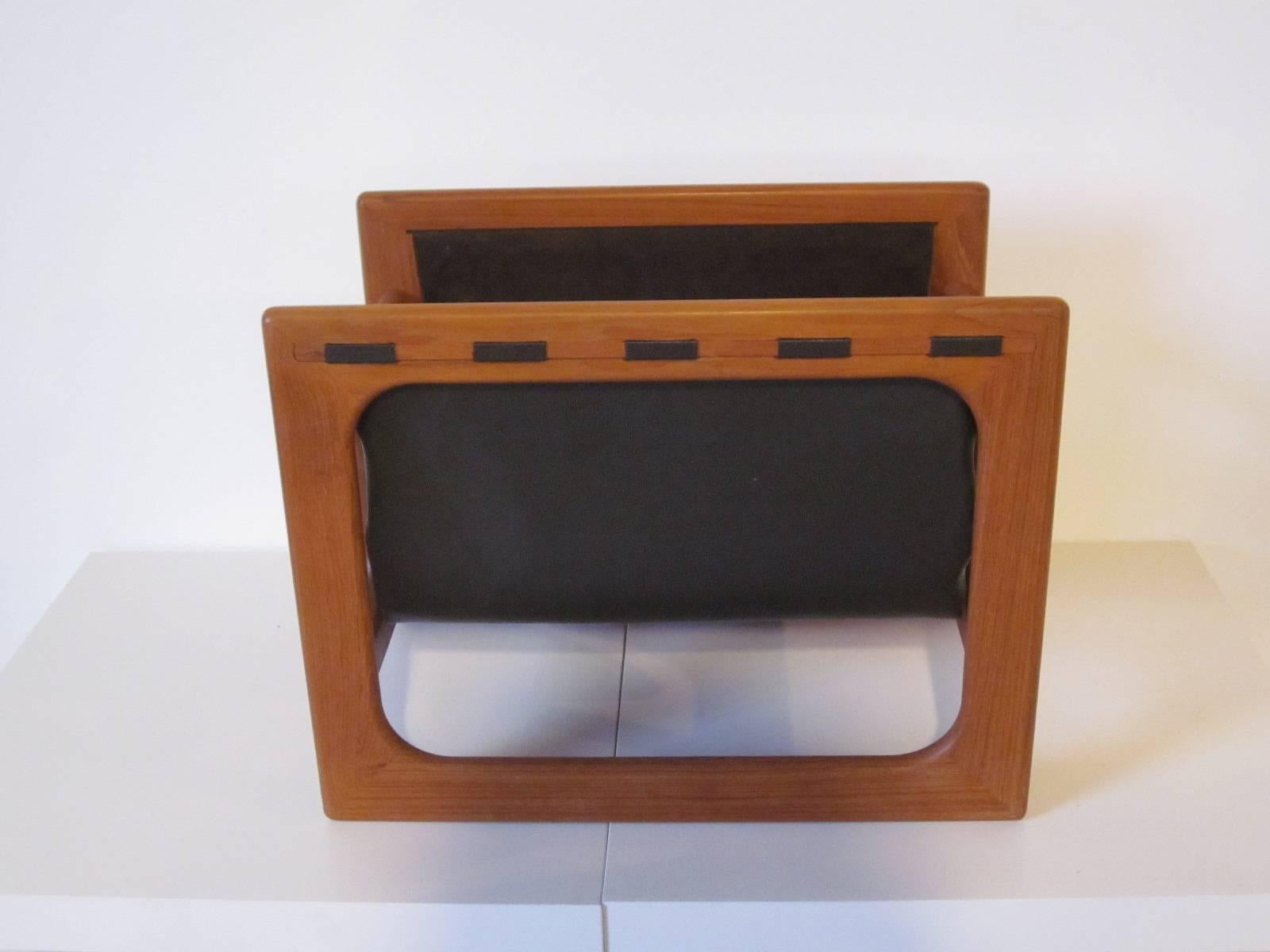 A well constructed sculptural teakwood magazine rack with suede sling holder, made in Denmark.