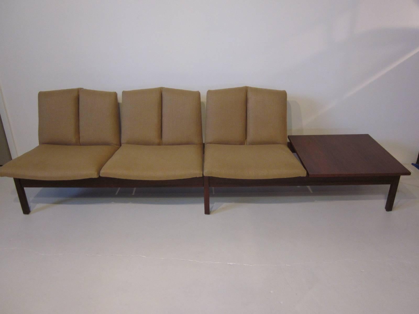 A Danish tandem modular seating set with three Italian linen covered seats in a medium dark tan tone with a walnut side table resting on a beautifully constructed solid walnut frame. Well designed and built with quality materials, home or office use.