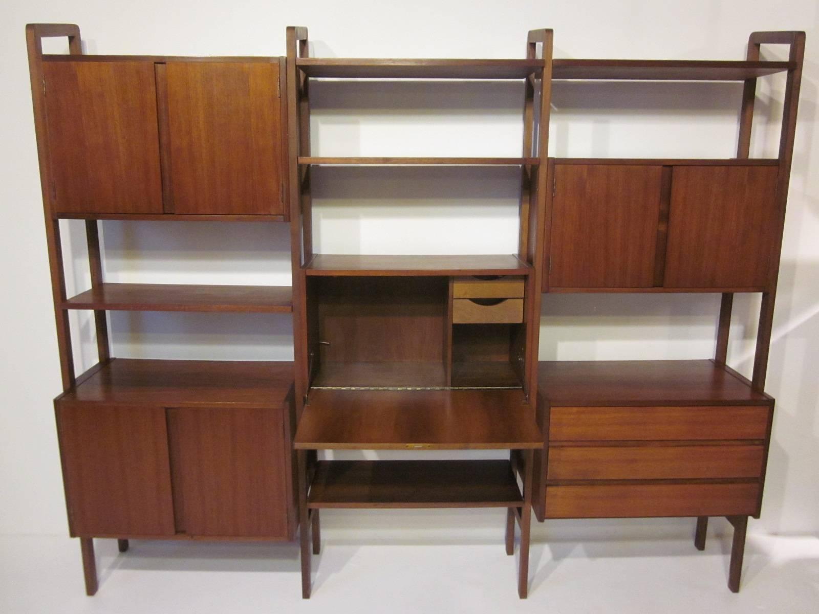 A three section walnut wall unit with center desk and drawers, three double door storage boxes with shelves, one three-drawer box and four adjustable shelves. It's free standing so no need for wall mounting or unneeded holes or ceiling mounts like