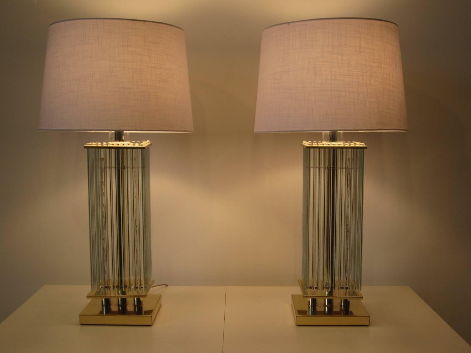 A pair of Scioari brass and hanging glass rod table lamps with a total of 40 polished rods topped with a white linen shade. The lamps have a three way switch, one for a nightlight twinkle affect inside the rods, one turns on the main light and one
