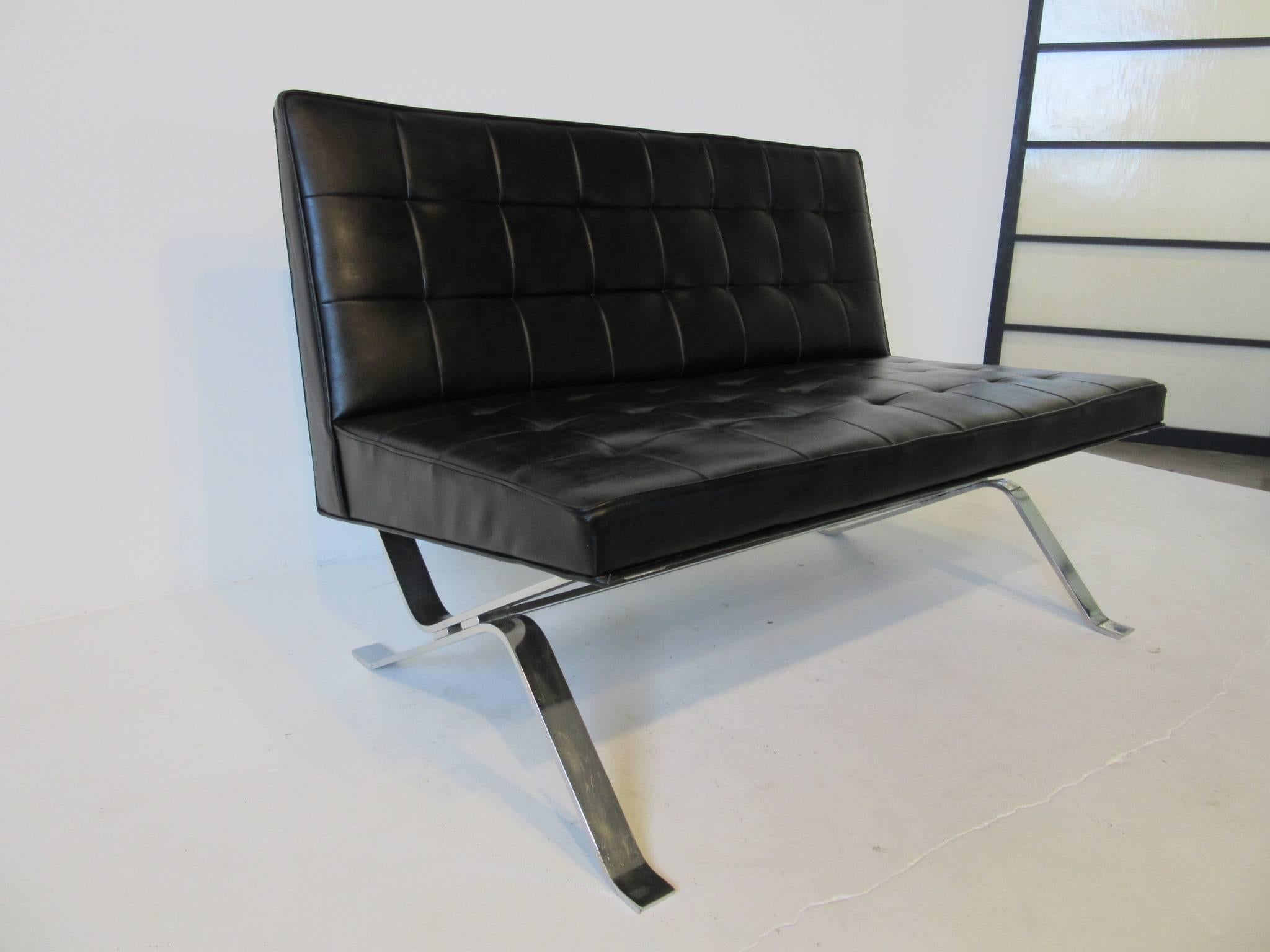 A black tufted Barcelona styled leatherette loveseat with chromed bar base in the manner of Ludwig Mies van der Rohe and designed by Robert Haussmann distributed by Stendig .