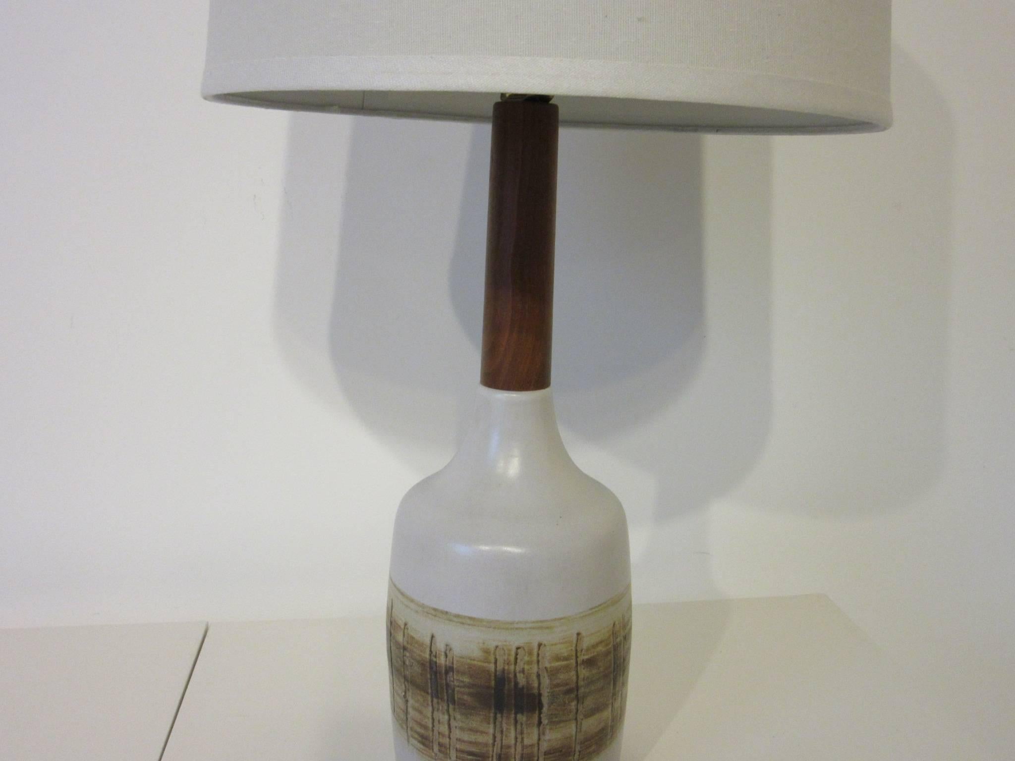 A pottery table lamp with incised and fired designs, teakwood stem and finial topped with a linen shade, artists signed to the lower reverse Martz , manufactured by Marshall Studios. This is the top choice for Mid-Century interiors.