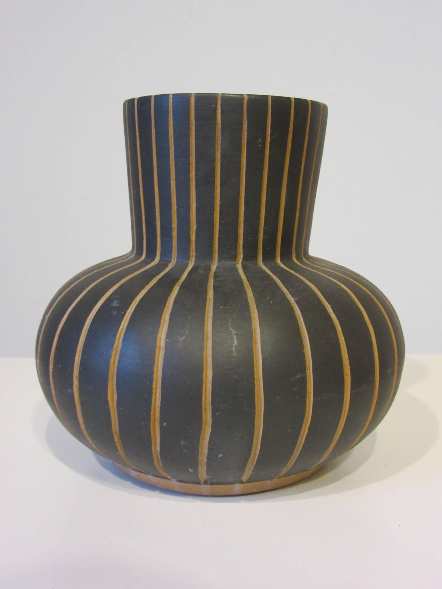 A simple and modernist styled incised art pottery vase with ebony tone body and clay under lines, inside has a warm green jade colored glaze, marked to the bottom Mexico/Contex - 7 G.