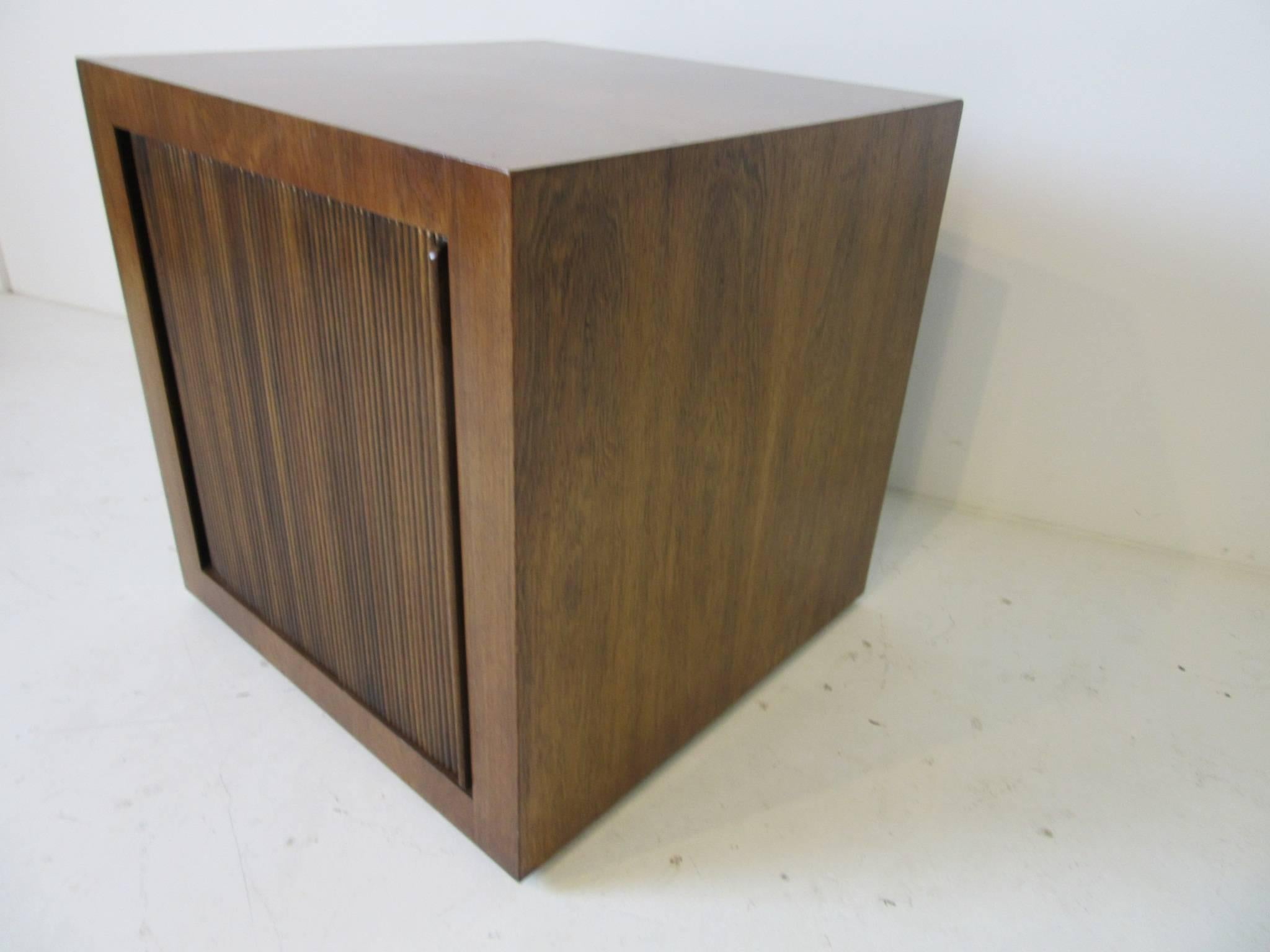A rolling bar cube in a rich Brazilian rosewood with a tambour door reveling storage and a bottle shelve with cut away area for larger bottles. This is a great item for that library, study or smaller space, retains the manufactures hang tag by the