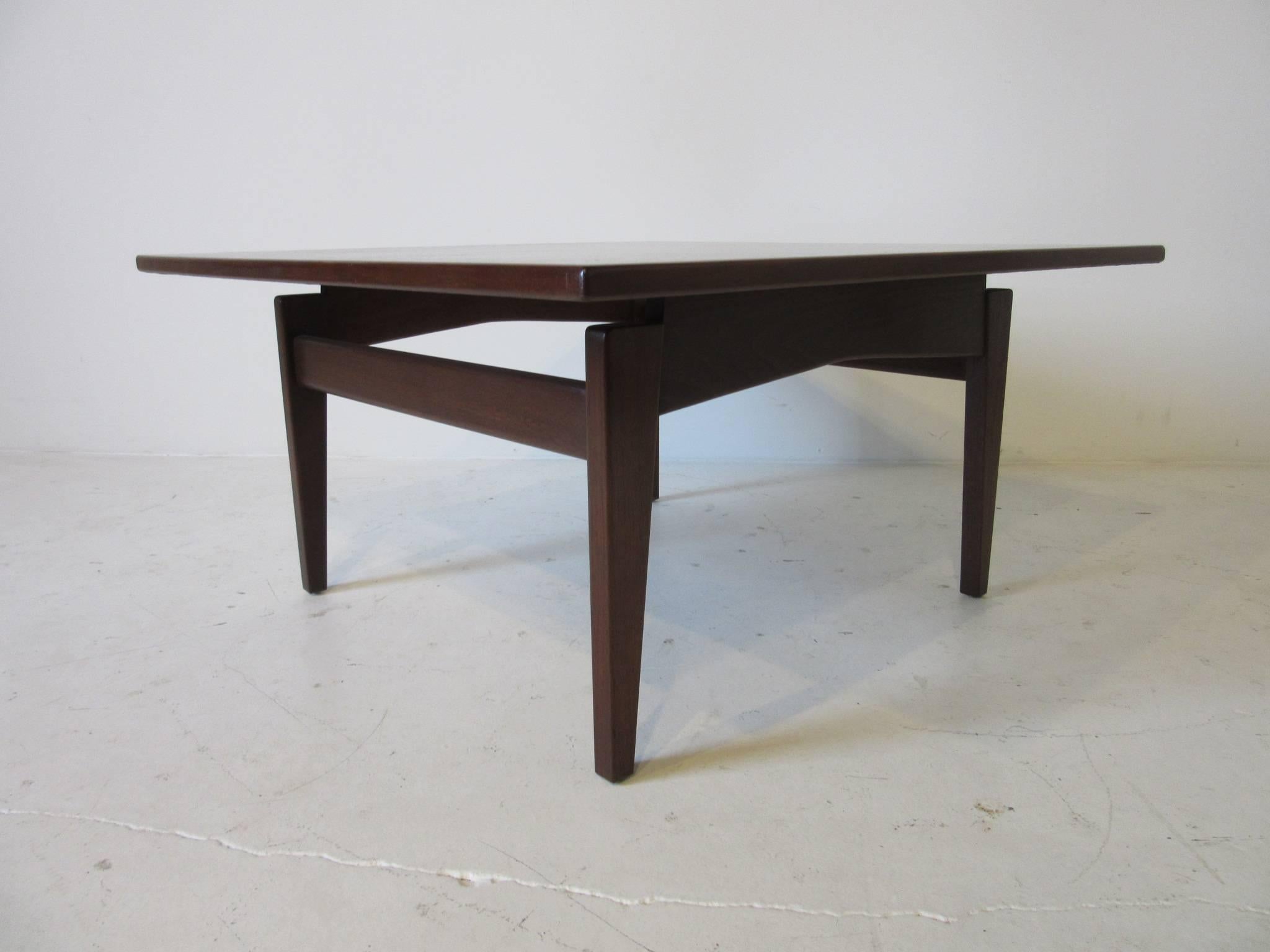 A Danish styled dark walnut floating top coffee table with straight stretchers and winged stretchers, retains the manufactures tag Jens Risom Design Inc.