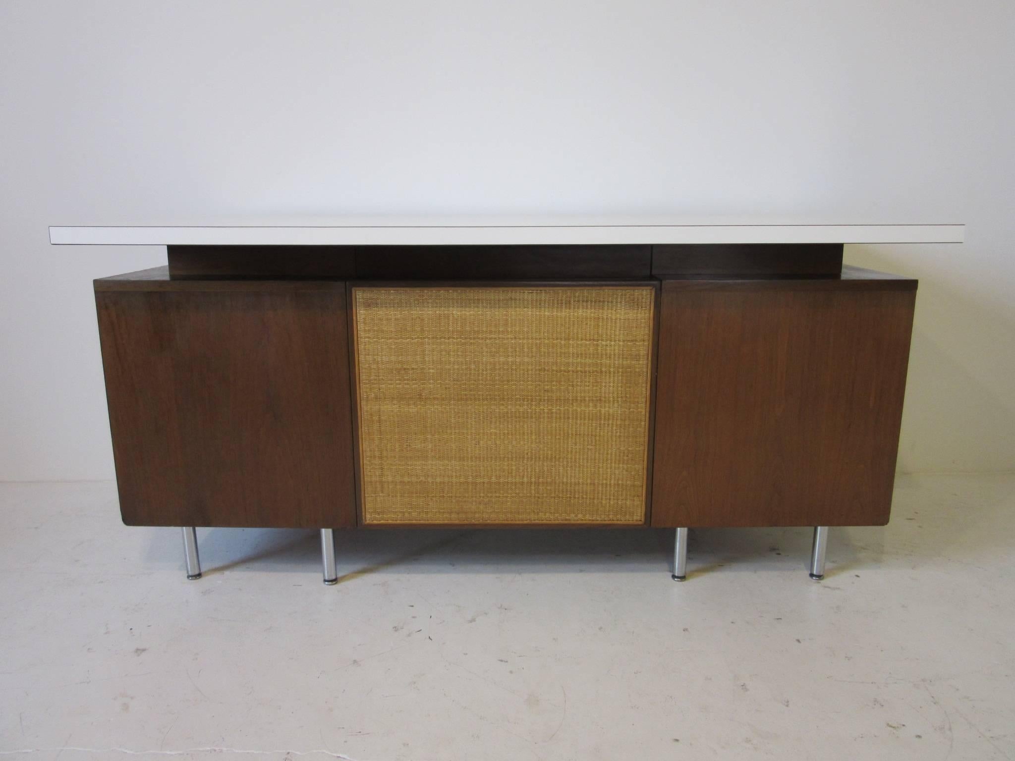 A walnut four drawer desk with aluminum J pulls, chromed steel legs, woven privacy panel and topped in white Laminate was designed and fitted for a
Bank building. The National Historic Landmark bank was designed by Eero Saarinen and was completed