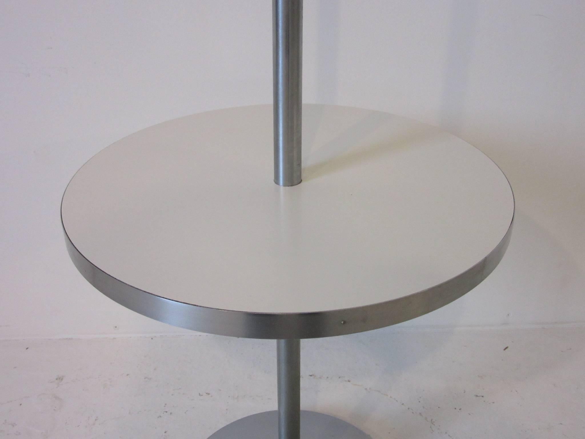 A brushed stainless steel pole floor lamp with integrated laminate drink table with metal base and original linen shade. Manufactured by the Nessen Lamp Company. The drink table measurement is 14