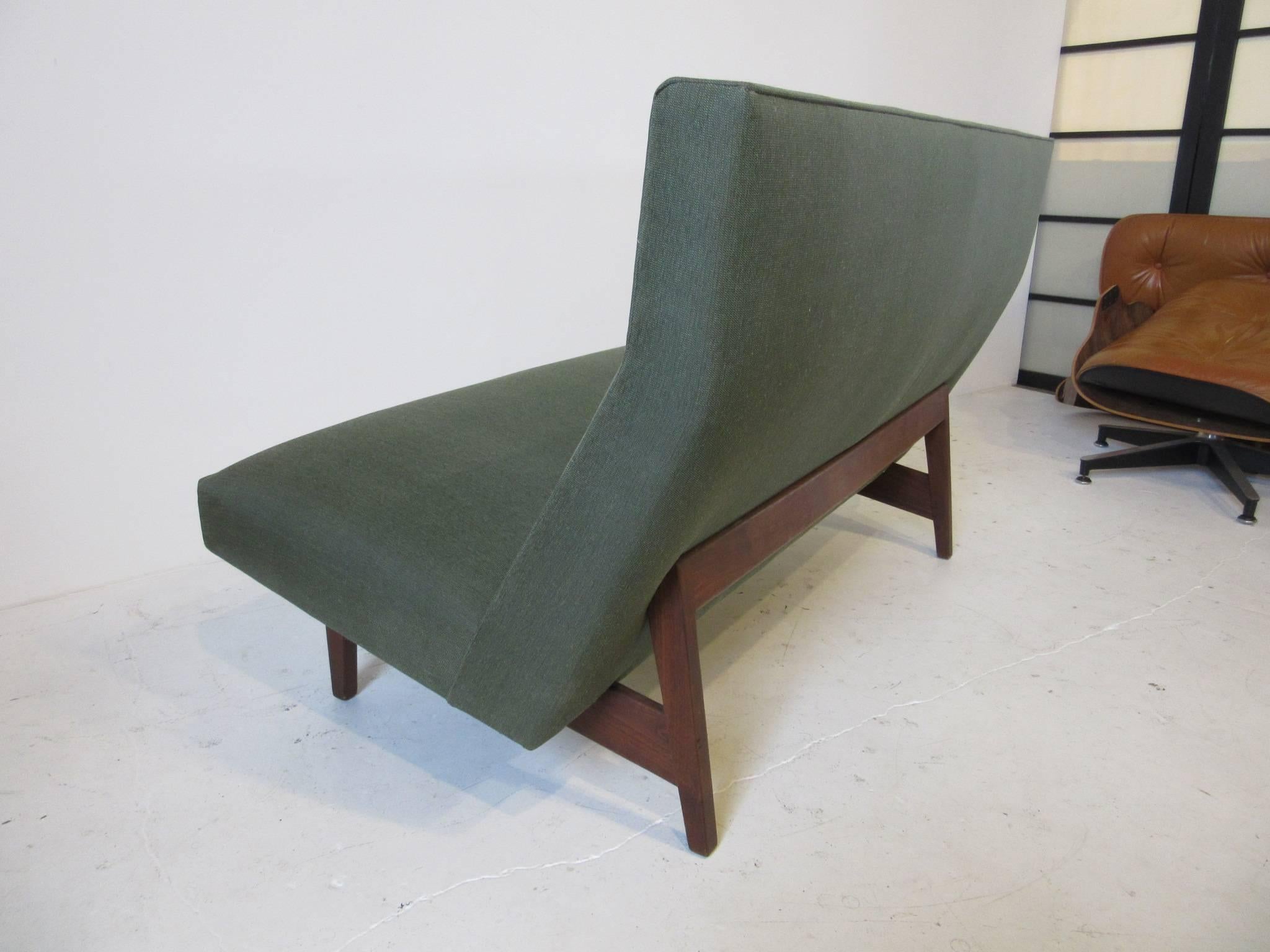 A Danish styled settee with walnut frame exposed in the rear and angled seat back with buttons upholstered in a tight moss green contract fabric. Manufactured by the Jens Risom Design company.