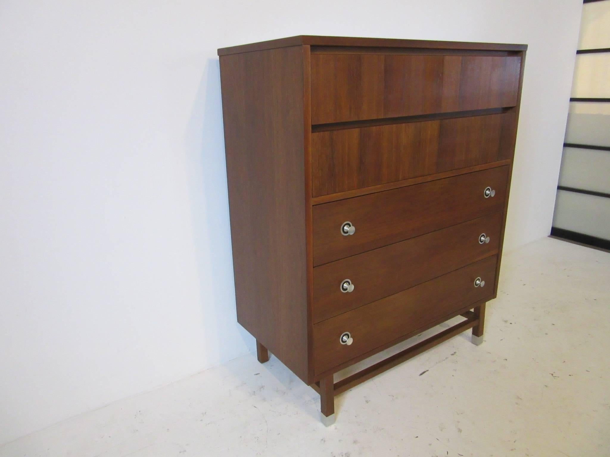 A five-drawer dresser chest in walnut with rosewood details, spun aluminum pulls and wood stretcher base with aluminum capped feet. Manufactured by the Stanley Furniture Company.