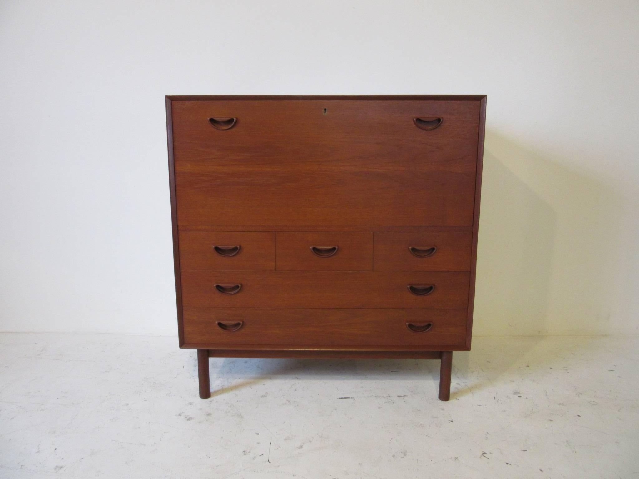 A medium dark teak wood chest with flip down locking front desk top with key, two slim pullout drawers with dividers and five lower drawers. Well designed and made with finger joints to the top edges and bottom, made in Denmark by Soborg Mobler, the