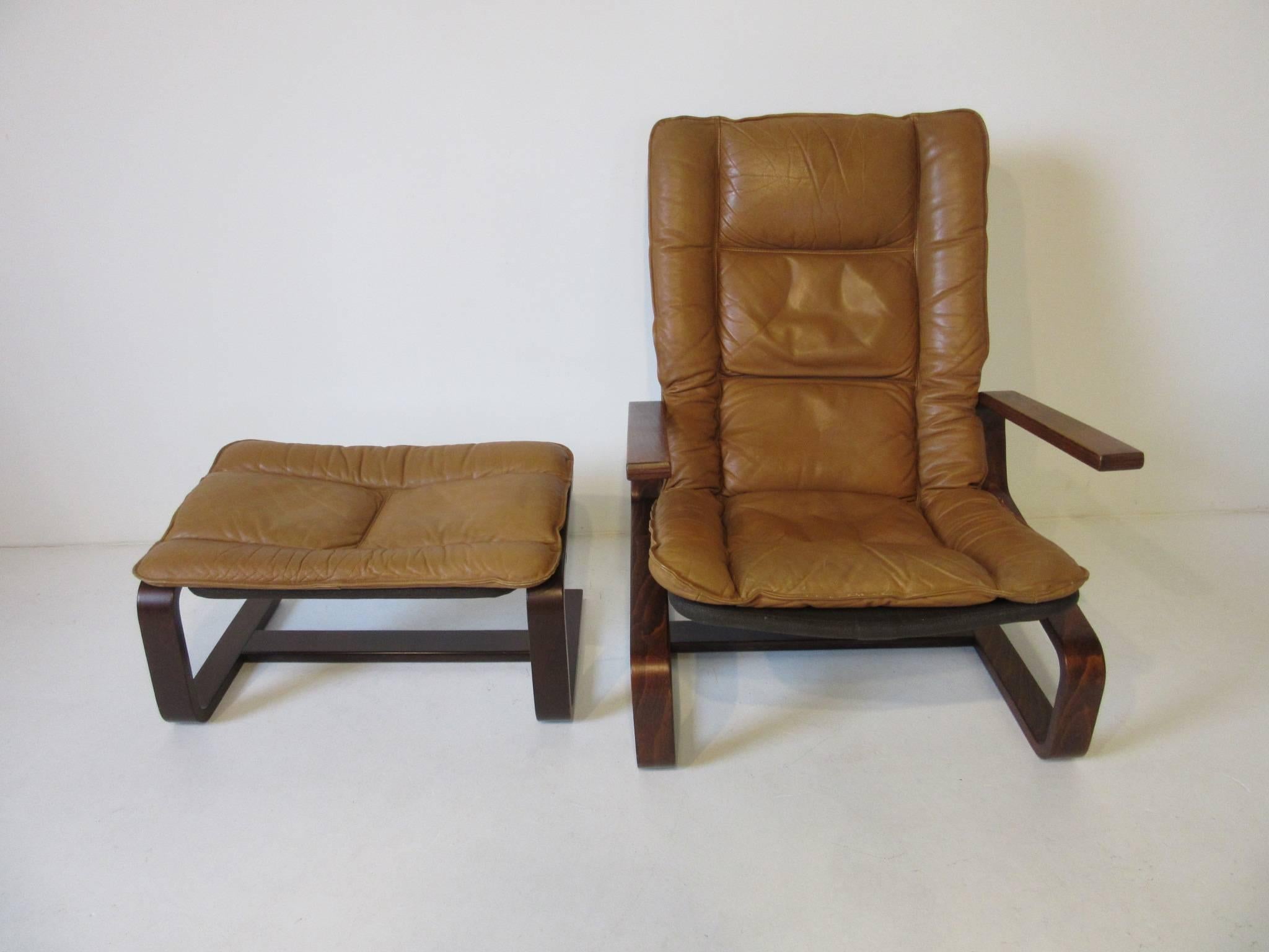 A Danish styled lounge chair with matching ottoman sitting on a dark sculptural bentwood base, with baseball glove colored soft and warm leather. Retains the manufactures labels made in Norway by the Westnofa Furniture company. The measurement for