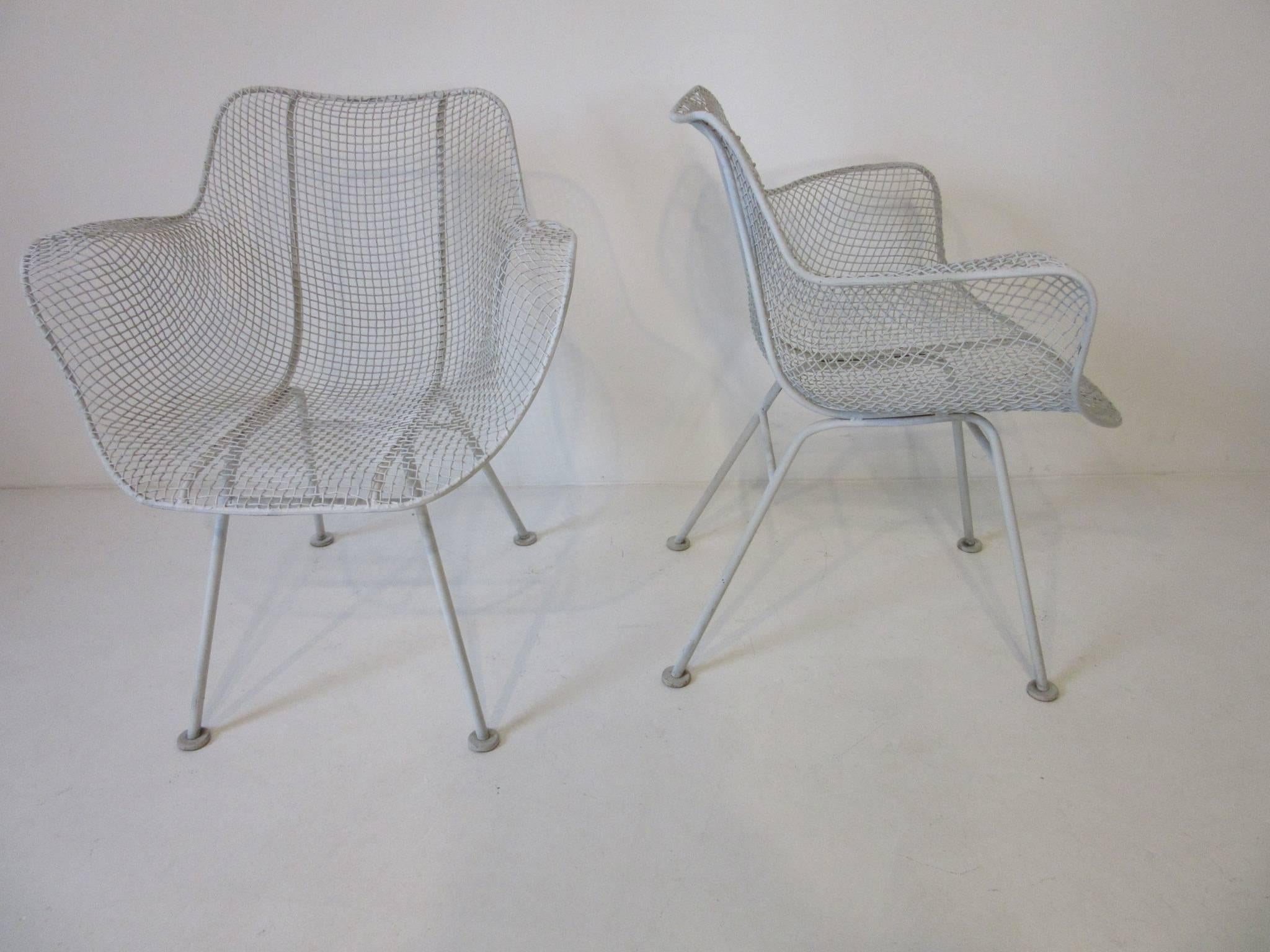 A pair of wire and iron molded and welded Sculptura armchairs in the style of Eames with foot pads and in their original finish. Great for a three seasons room, deck, porch or that cozy garden, manufactured by the Woodard Furniture Company.