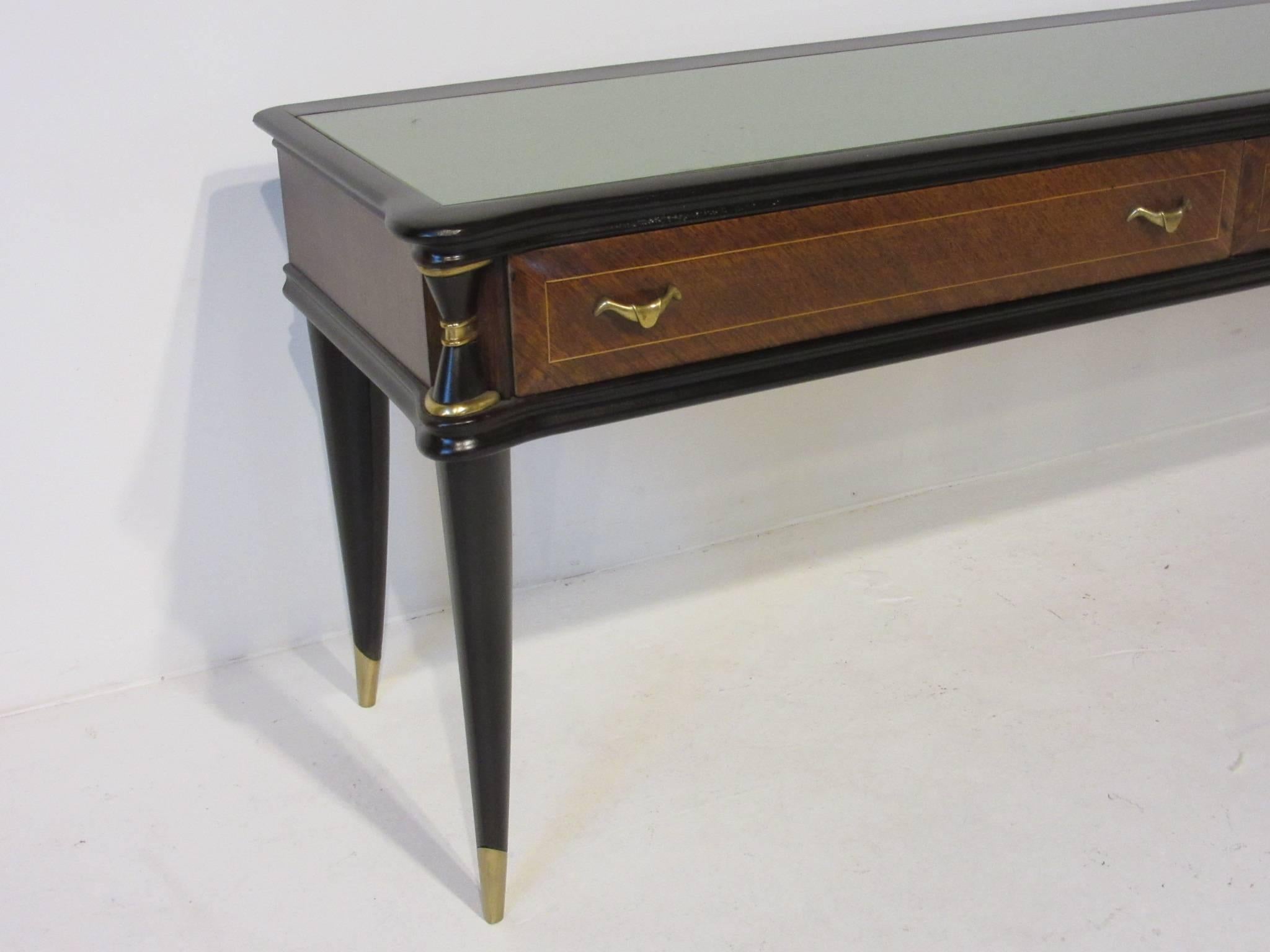 An Italian console table with frosted glass inserted top, brass details, two drawers and walnut with mahogany wood finishes.
